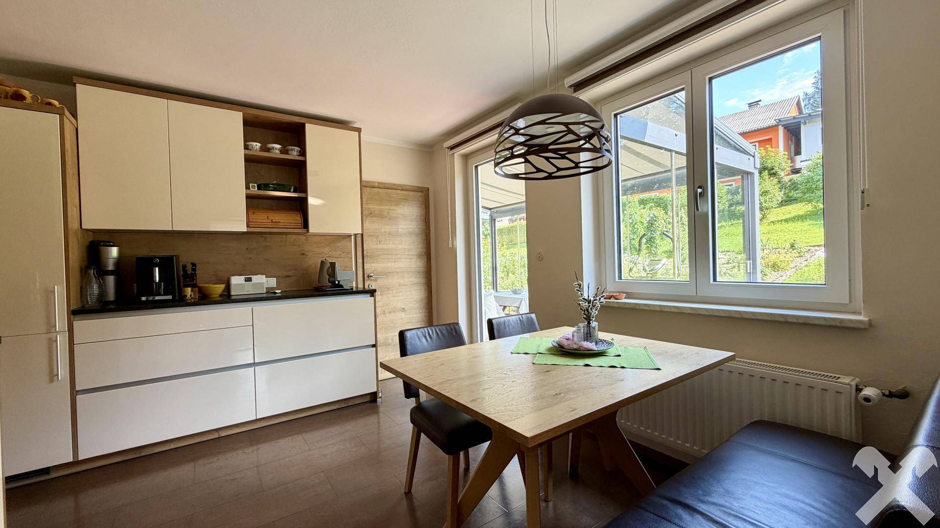 Helle Essküche mit modernem Esstisch, großen Fenstern und Zugang zum Wintergarten.