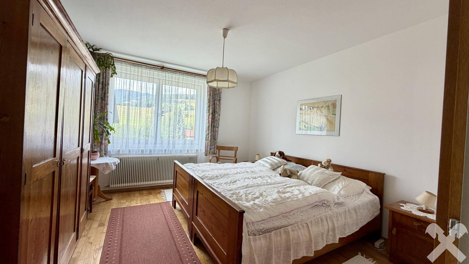 Geräumiges Schlafzimmer mit Doppelbett, Holzschrank und Blick auf die Landschaft.