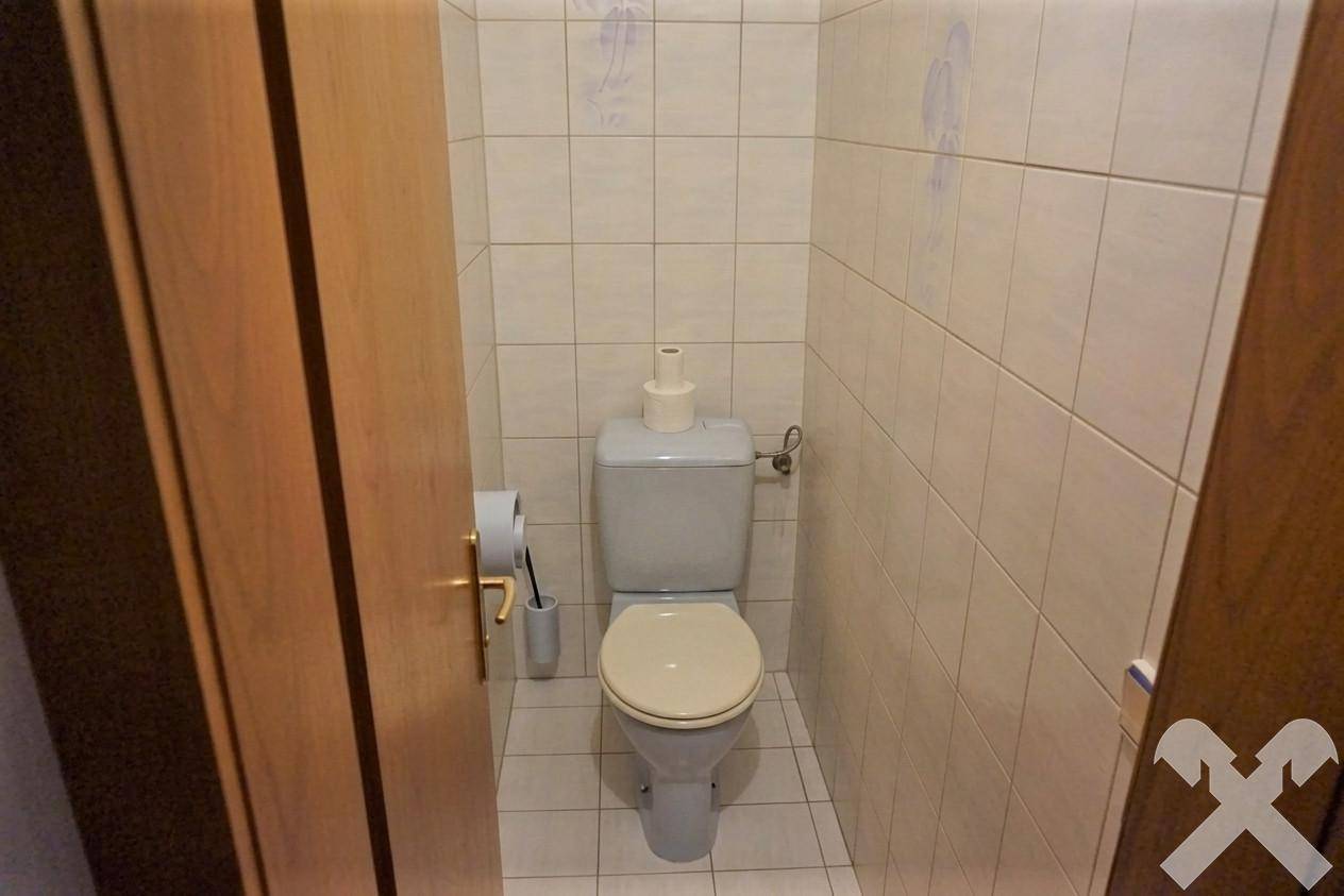 Separate Toilette mit hellen Fliesen und Standard-WC, praktisch und gut gepflegt.