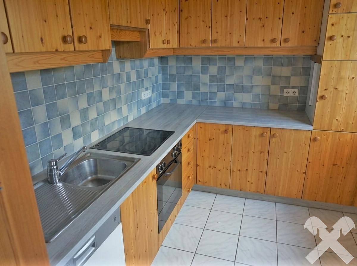 Funktionale Küche mit Holzschränken, blauen Fliesen und integriertem Kochfeld und Spüle.