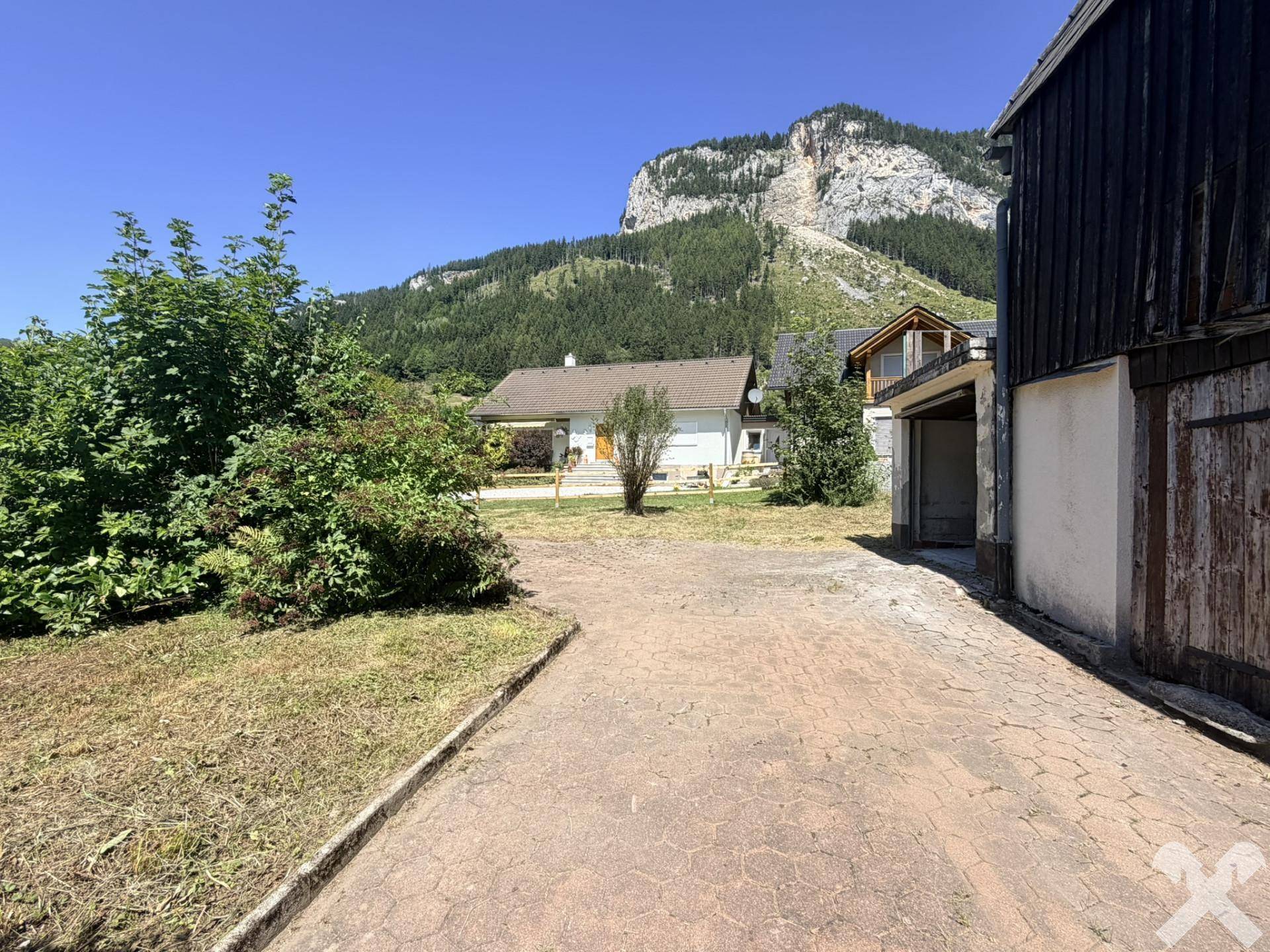 Einfahrt und Grundstück mit Blick auf die umliegende Berglandschaft unter klarem Himmel.