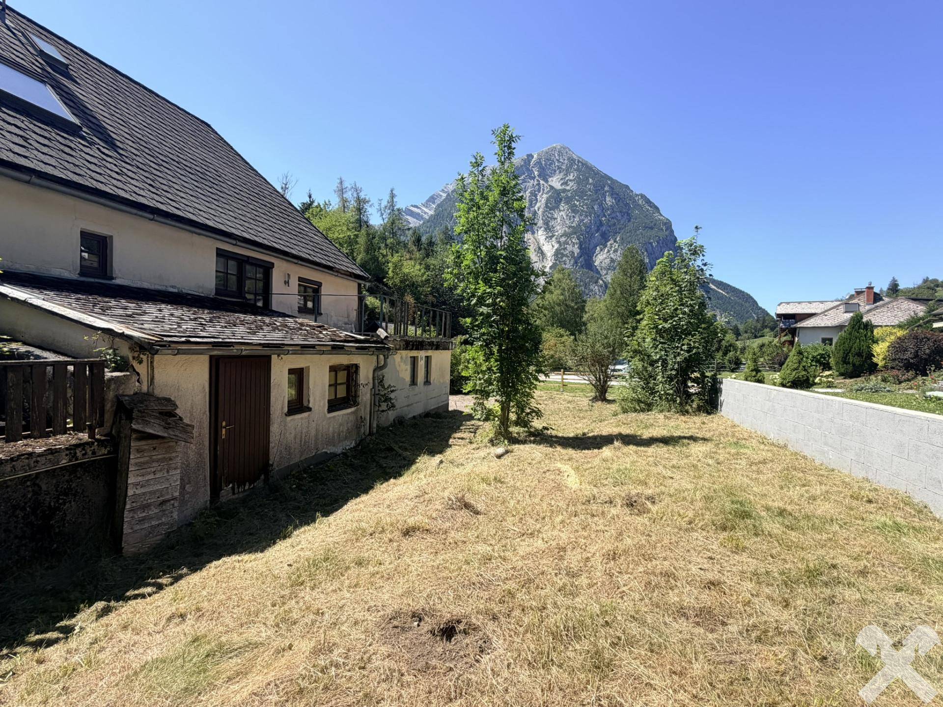 Seitenansicht des Hauses mit großem, trockenem Gartenbereich und beeindruckendem Bergblick.