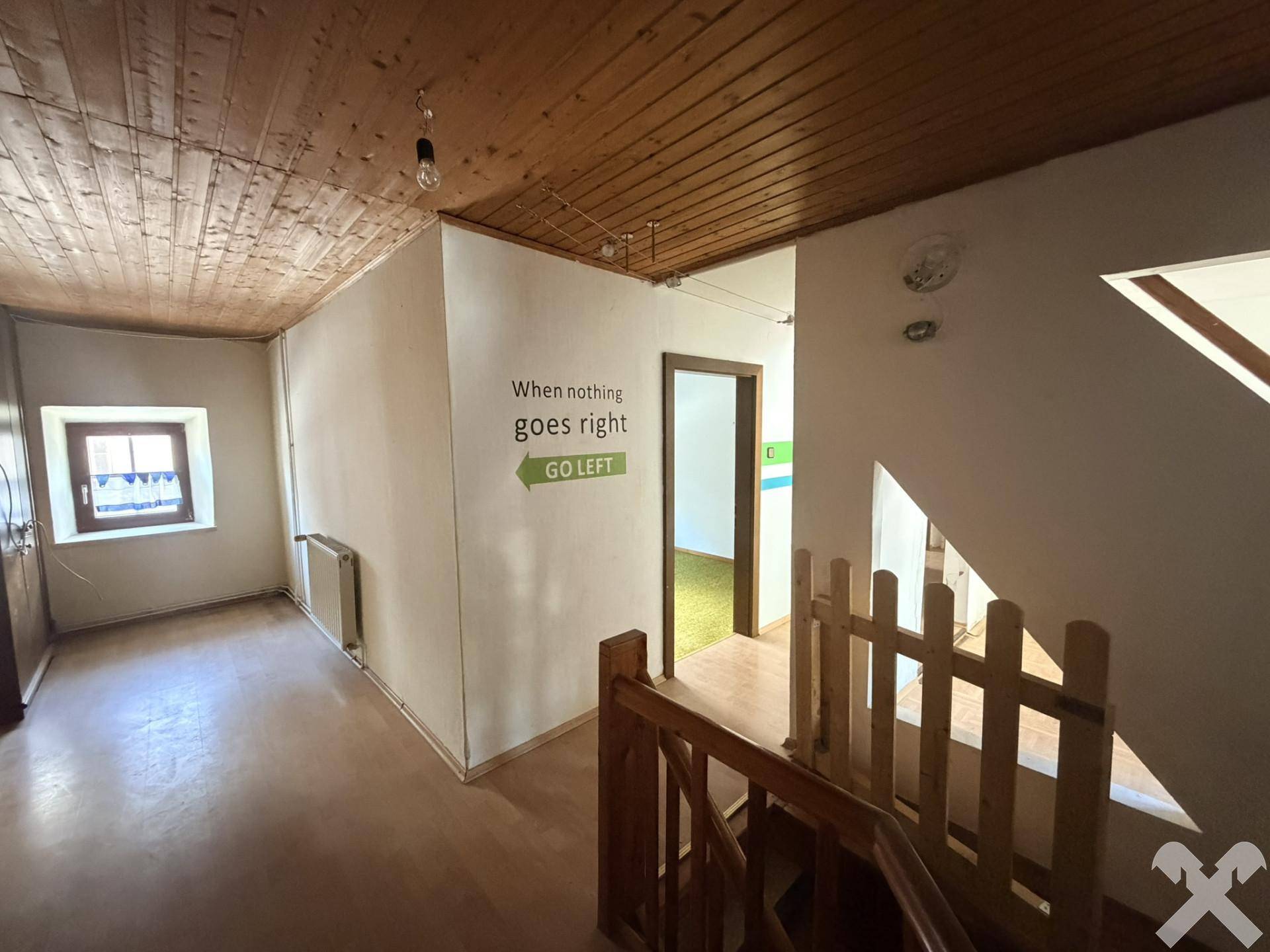 Heller Flur mit Holzdecke, Fenster und Treppenaufgang, dekoriert mit einem Wandspruch.