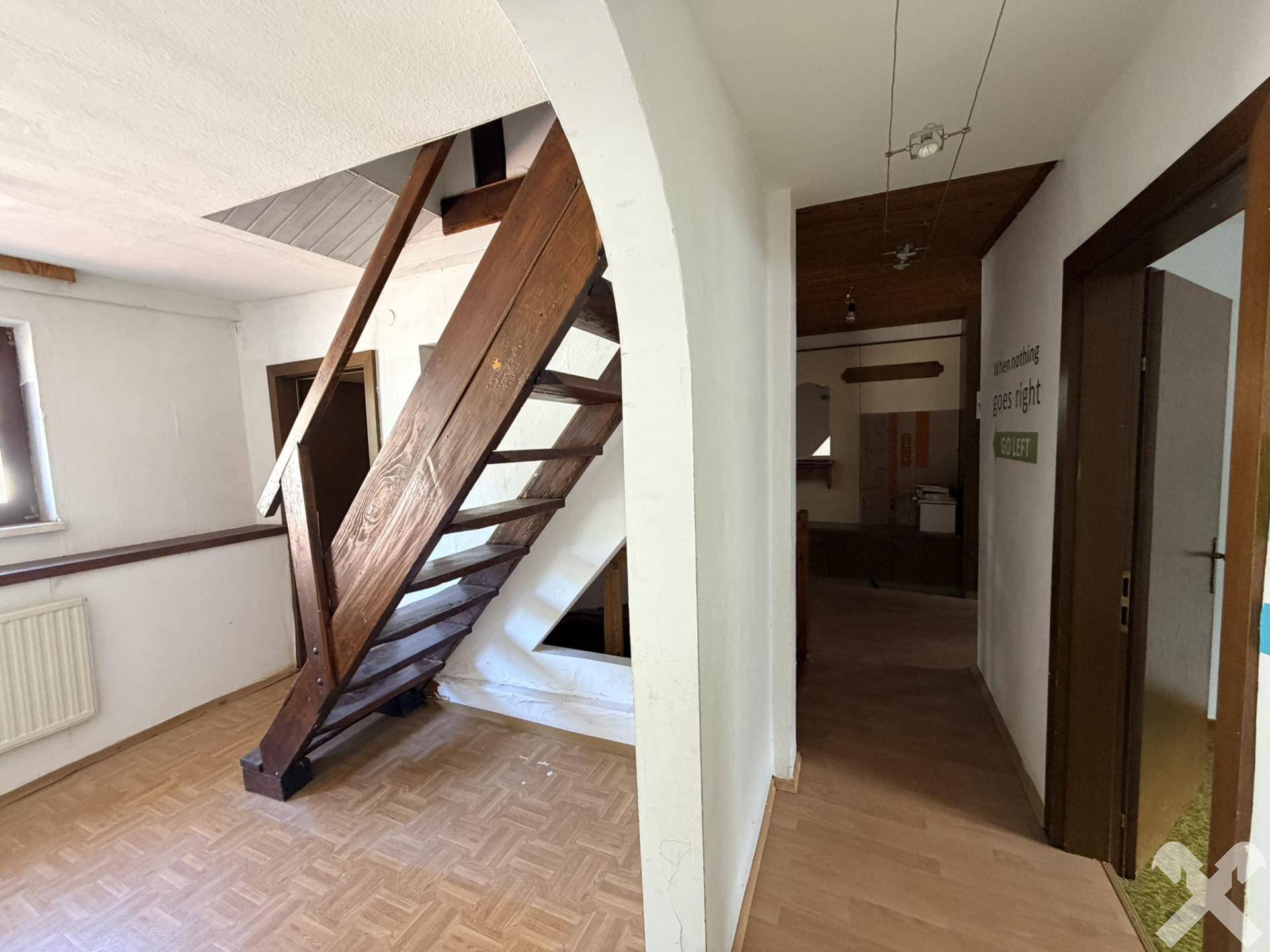 Heller Flur mit Holztreppe und Laminatboden, der zu weiteren Räumen führt.