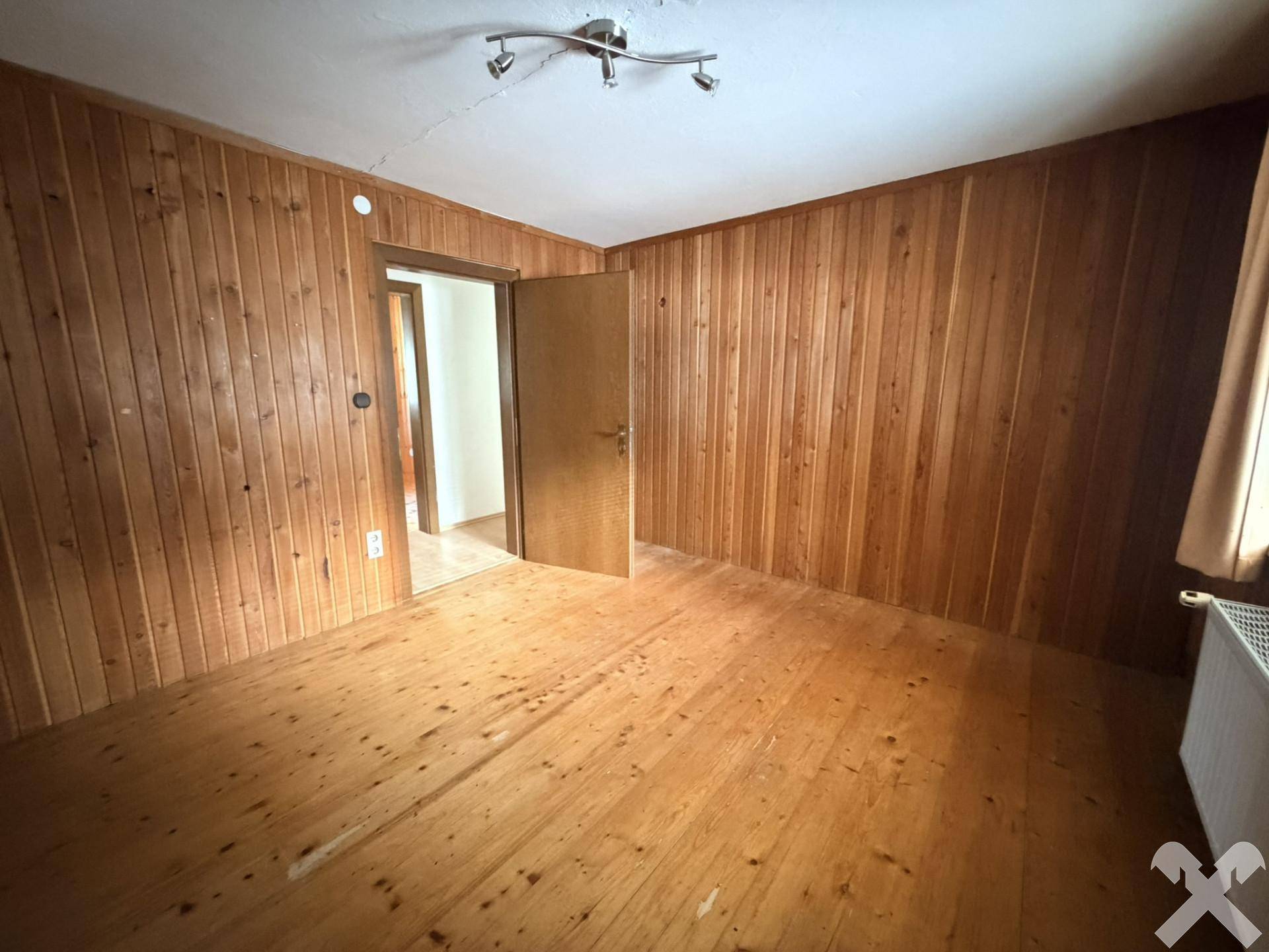 Gemütliches Zimmer mit holzvertäfelten Wänden und Holzdielenboden.