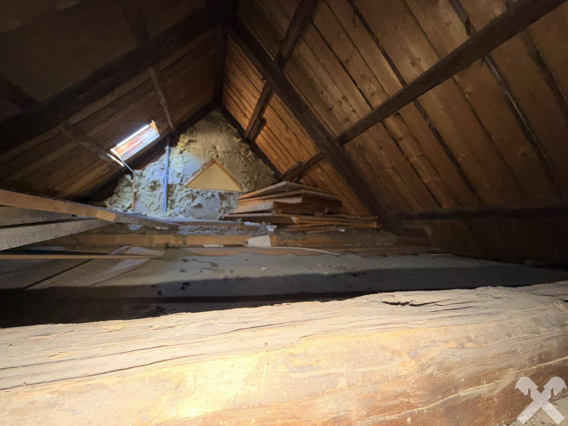 Hellerer Blick in den unfertigen Dachboden mit sichtbarer Holzkonstruktion und natürlichem Lichteinfall durch das Dachfenster.
