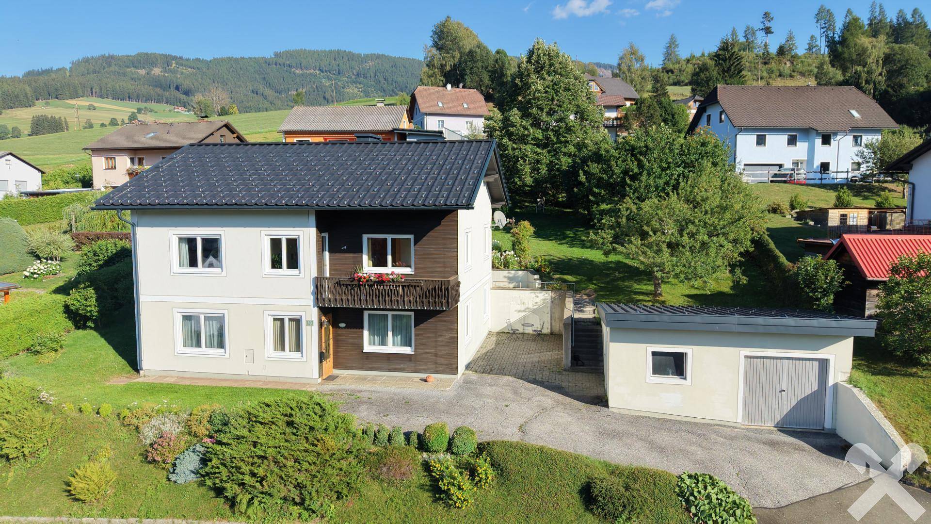 Freistehendes Einfamilienhaus mit Balkon und Garage in ländlicher Umgebung.