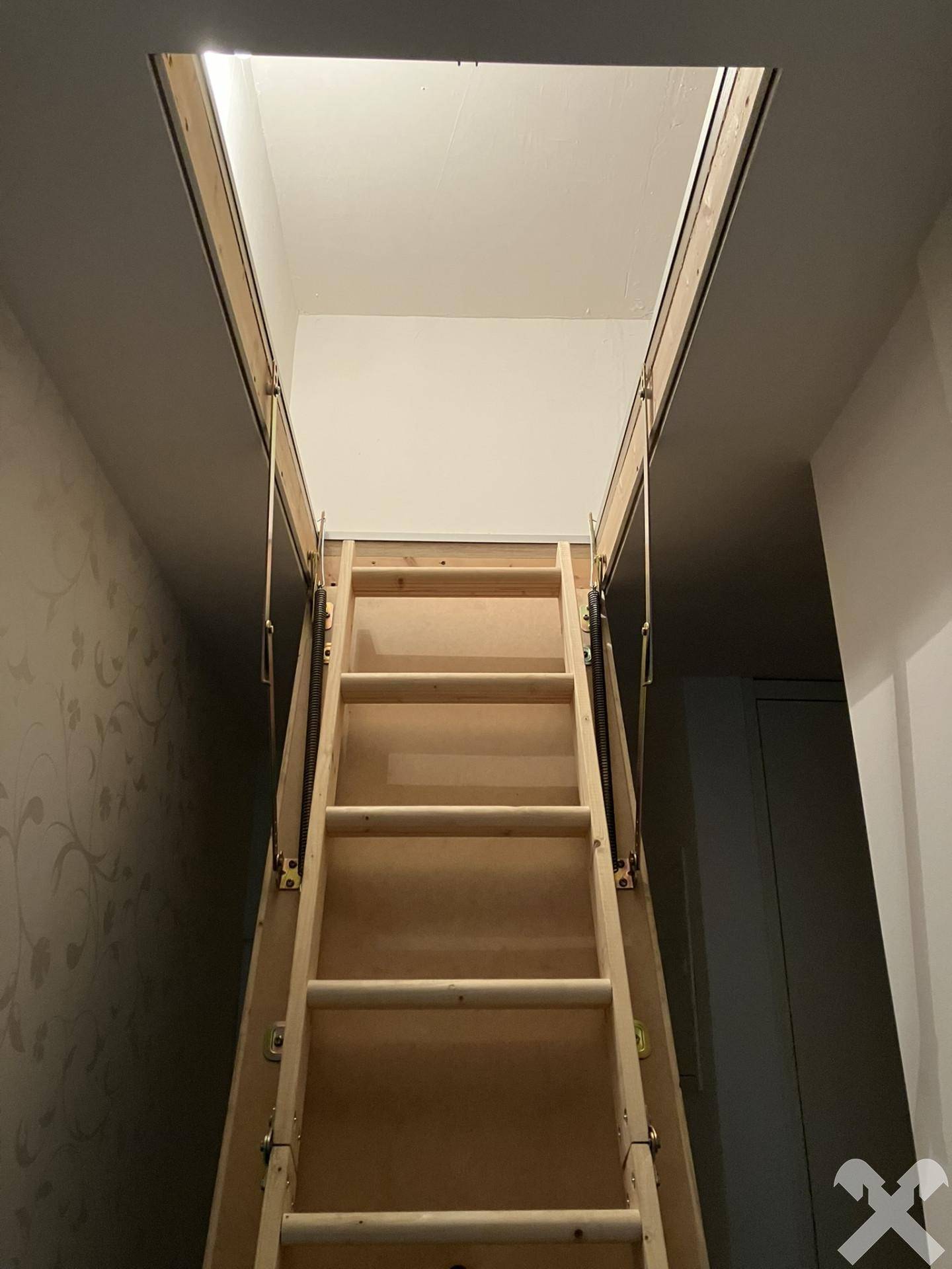 Ausziehbare Holzleiter zum Dachboden, bereit für den Zugang zu zusätzlichem Stauraum.