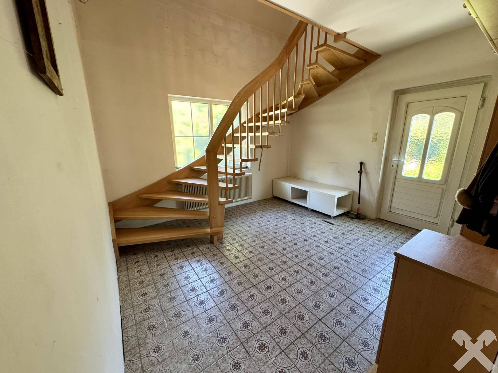 Heller Eingangsbereich mit Holztreppe und gemusterten Fliesen, einladend gestaltet.
