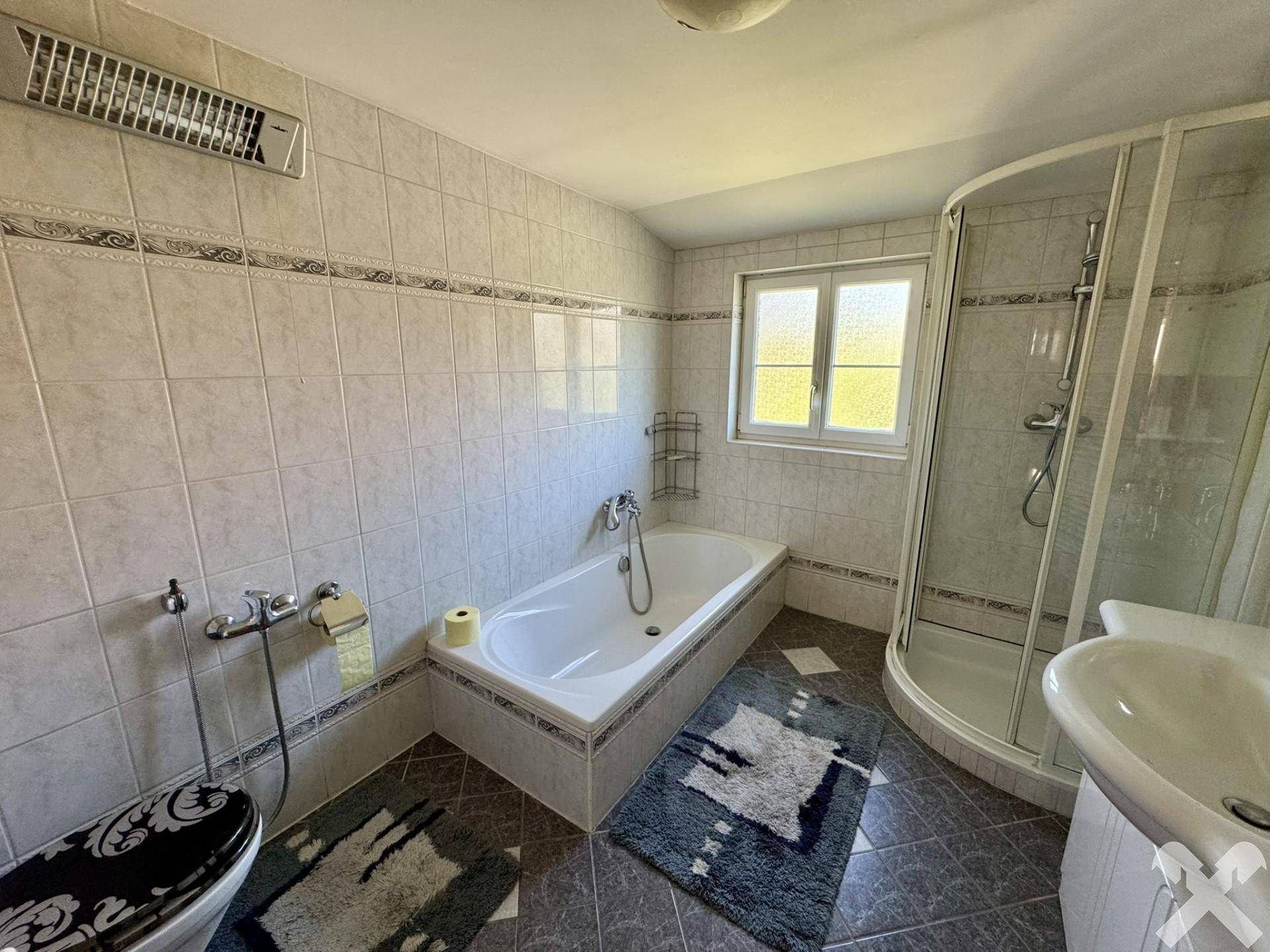 Helles Badezimmer mit Badewanne, Duschkabine und hellen Fliesen.