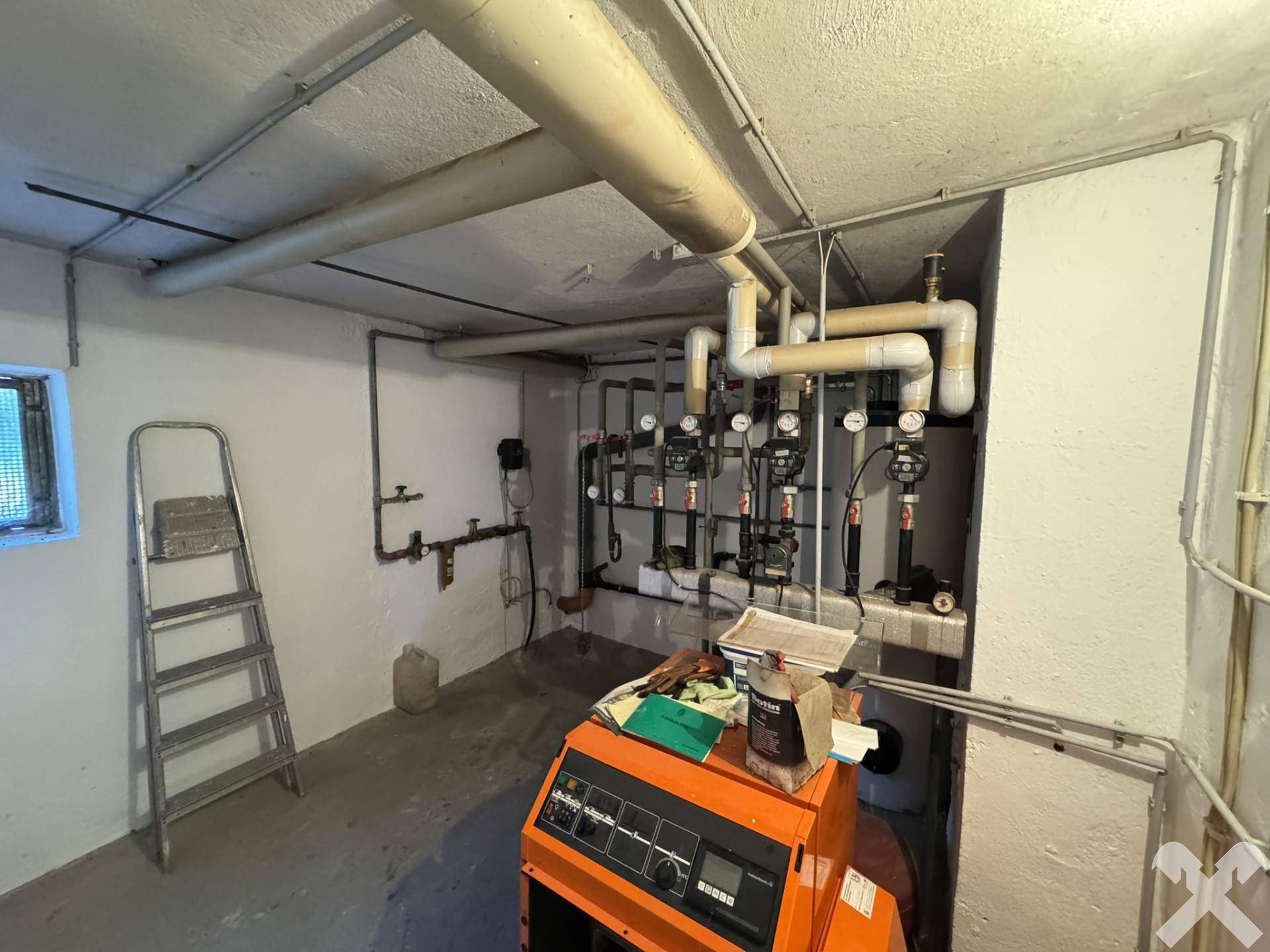 Heizraum im Keller mit Heizungsanlage und sichtbaren Rohren.