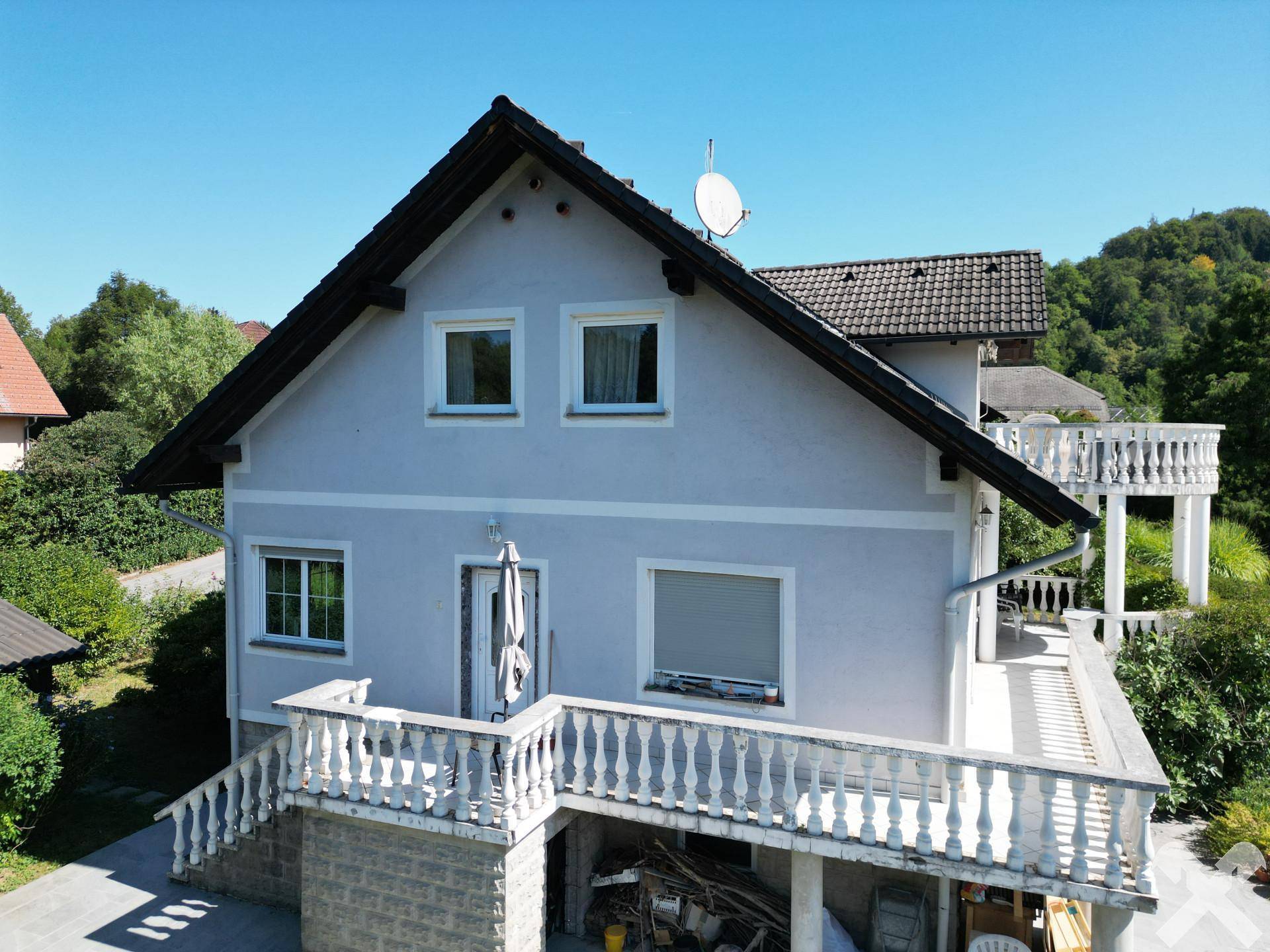 Vorderansicht des Hauses mit Eingangsbereich und Balkon, umgeben von Grün.