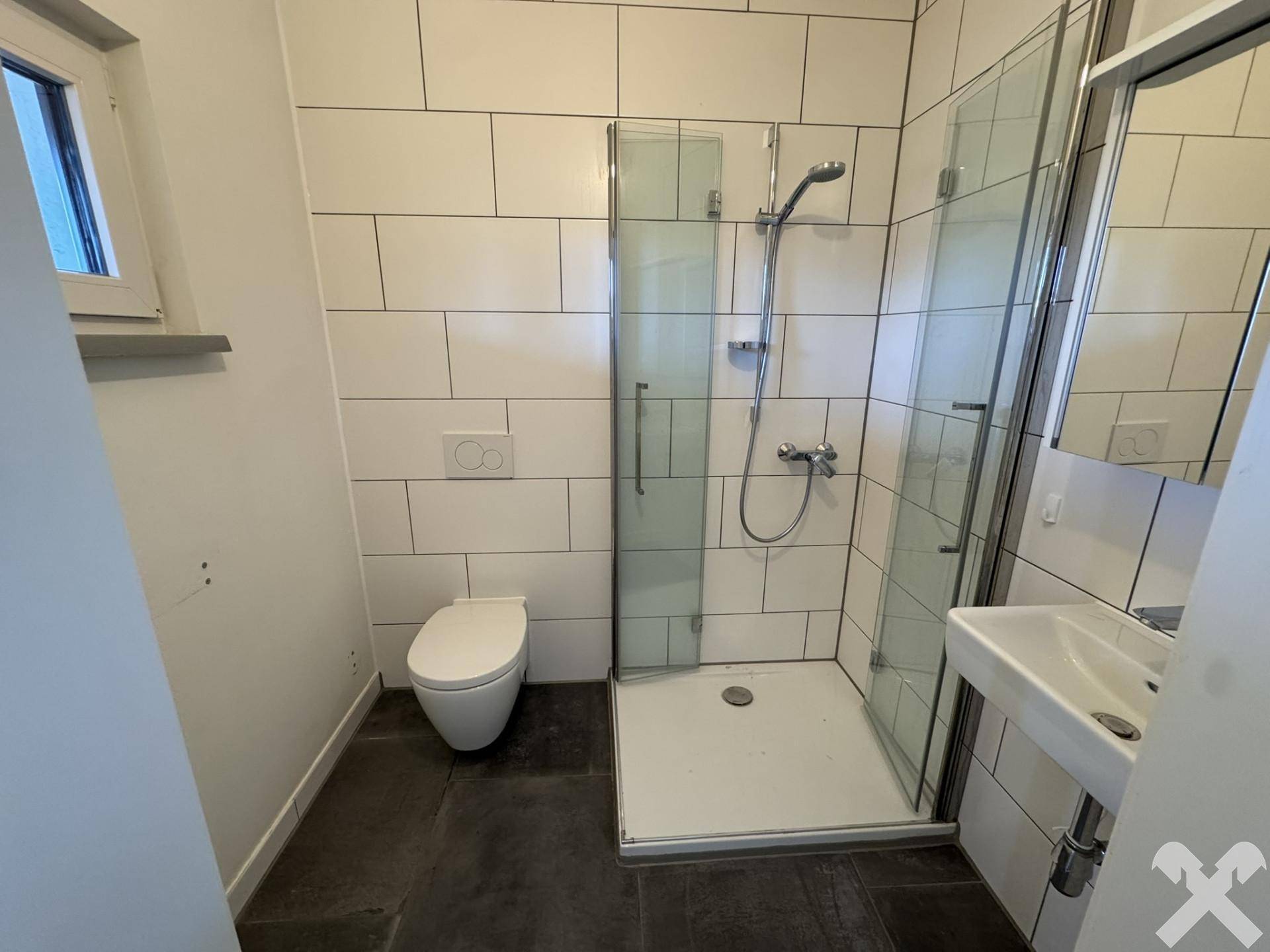 Modernes Badezimmer mit Dusche, WC und Waschbecken, hell gefliest.