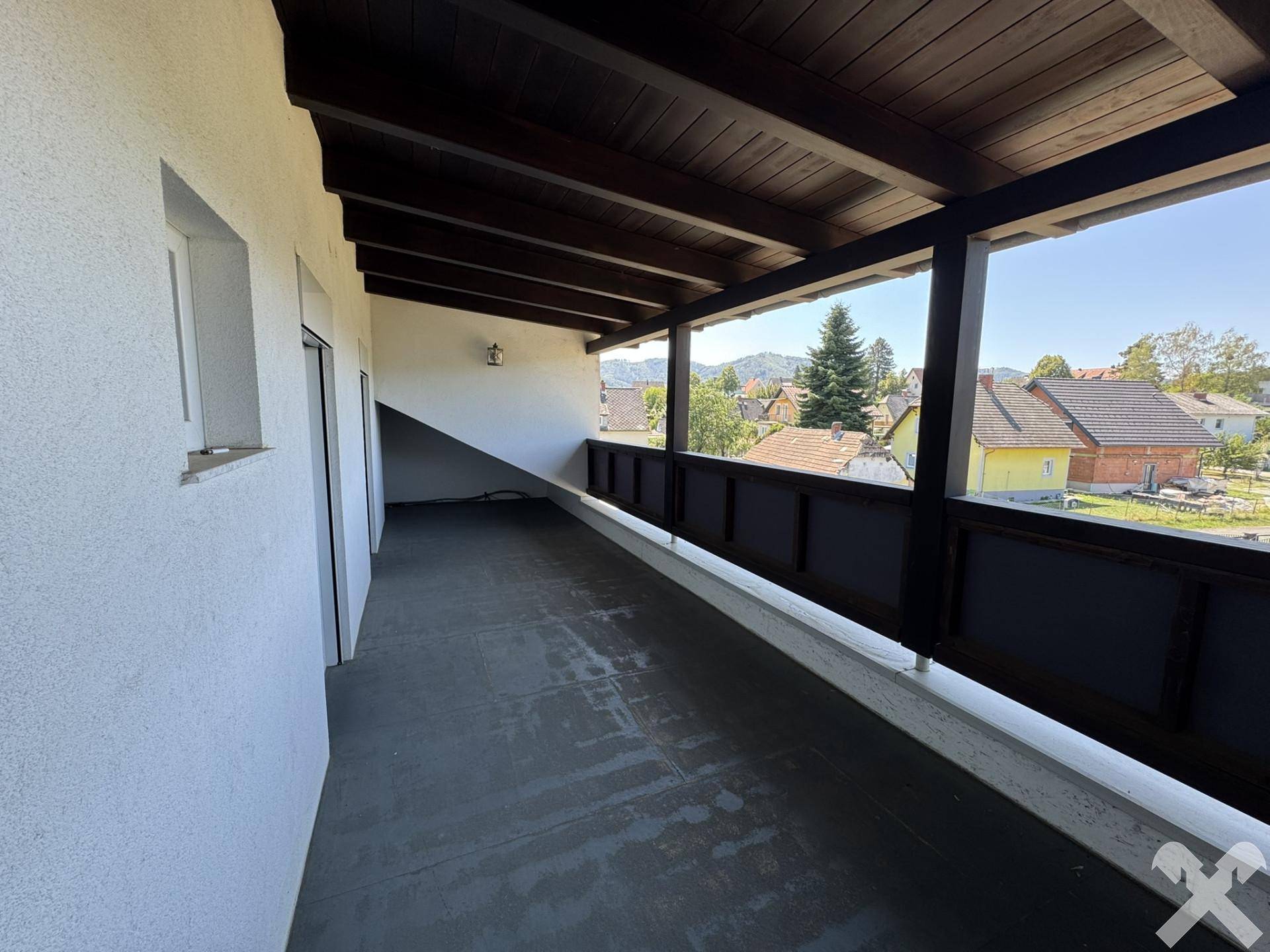 Großer überdachter Balkon mit Holzdach und weitem Blick über die Landschaft.