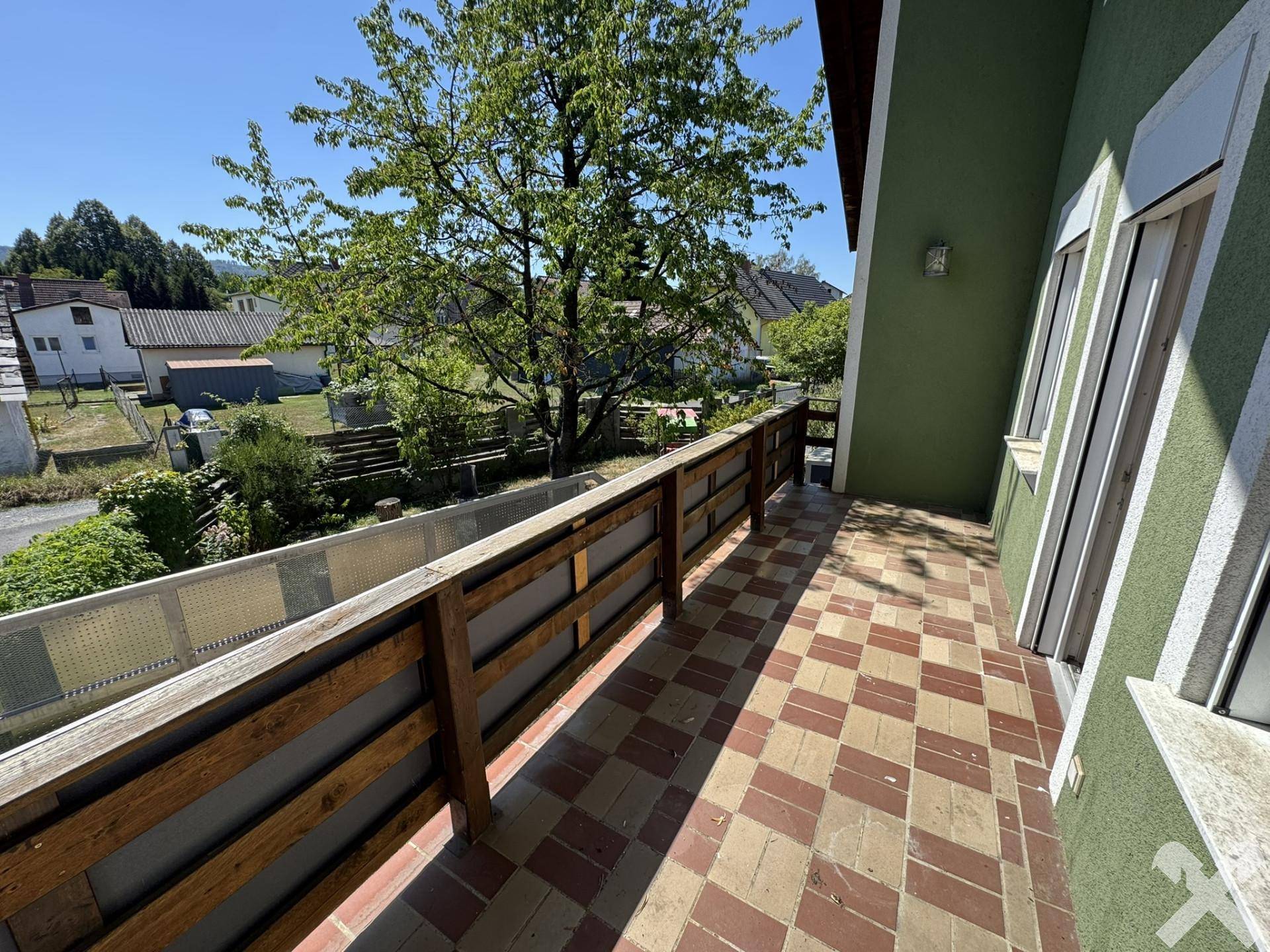 Langer Balkon mit Fliesenboden und Holzbalken, bietet Blick auf die Umgebung.
