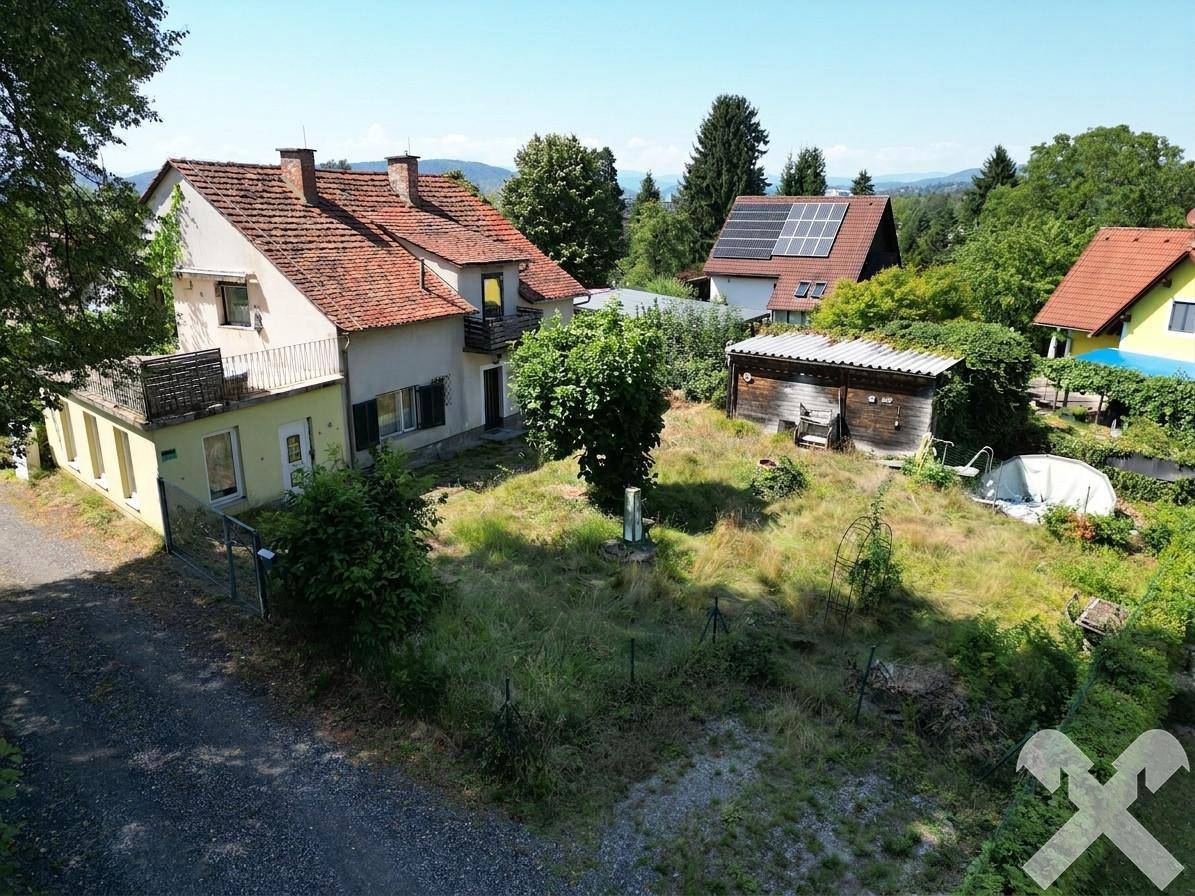 Luftaufnahme des Hauses mit großem Garten, Nebengebäude und umliegender Naturlandschaft.