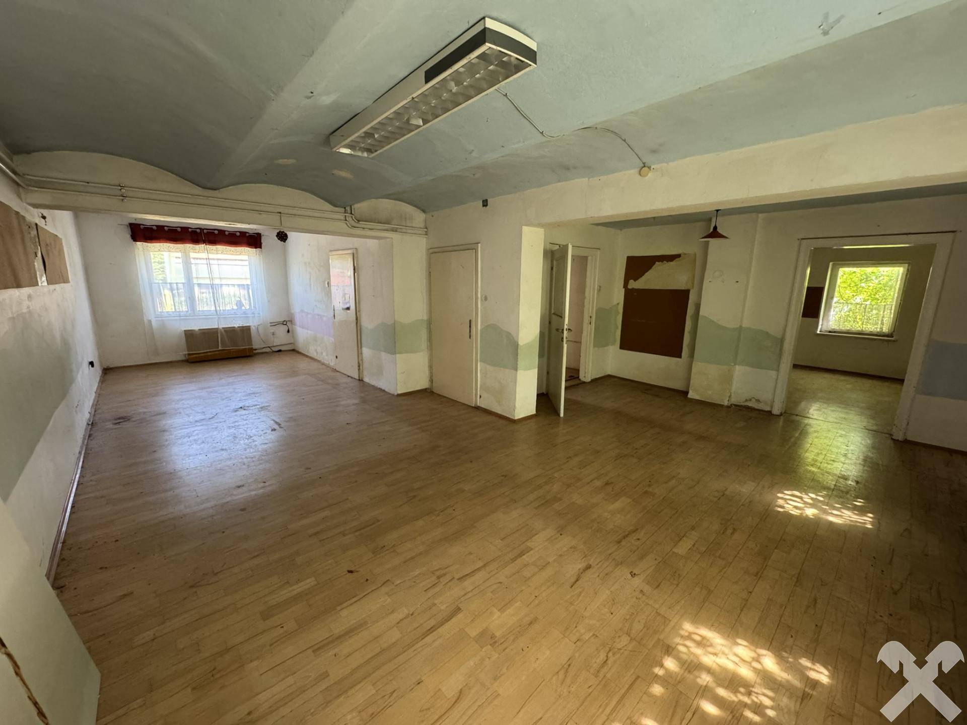 Geräumiger Innenraum mit Holzboden, weißen Wänden und einer gewölbten Decke, bereit zur Renovierung.