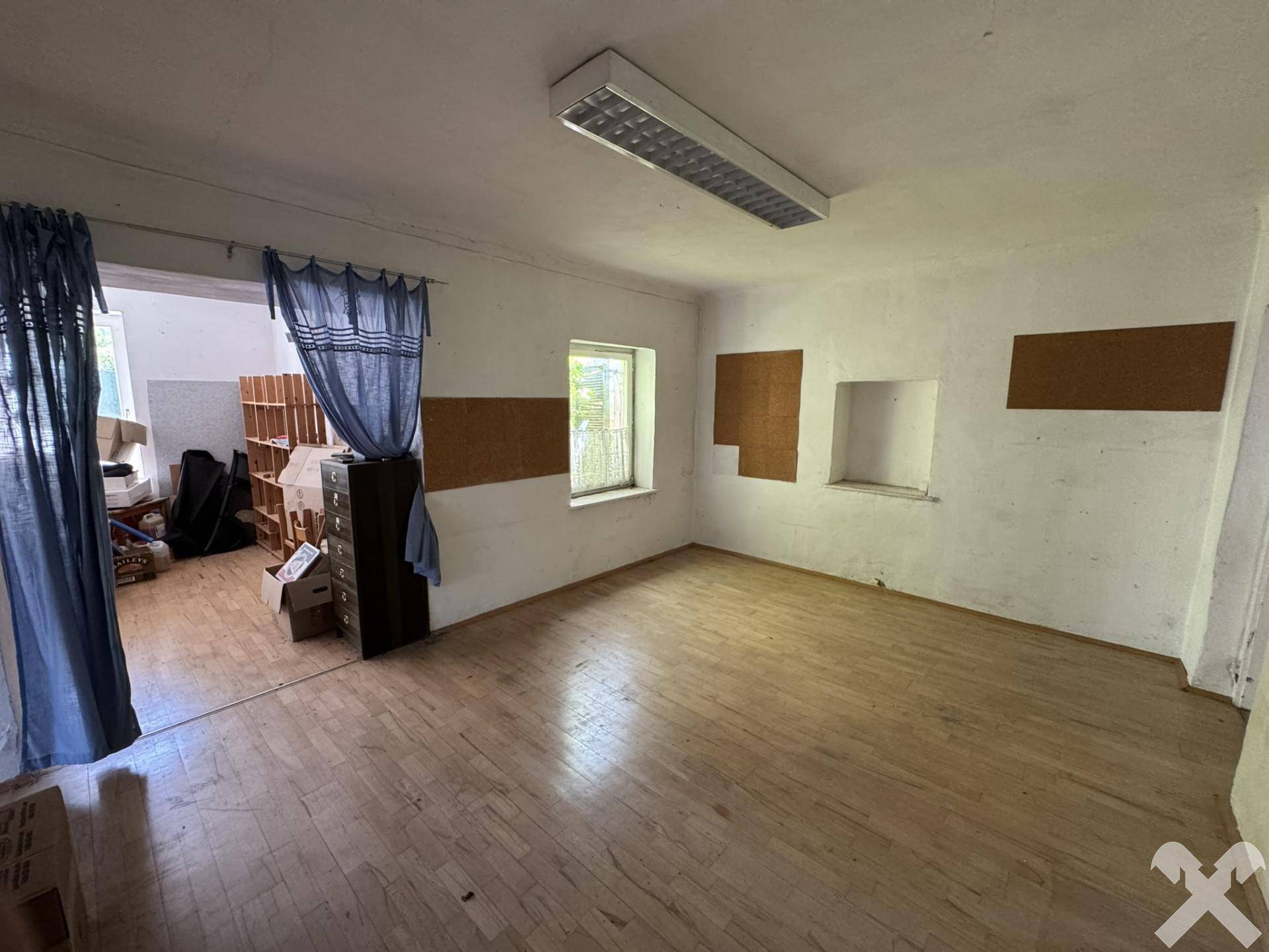 Heller Innenraum mit Holzboden und Fenster, das viel Tageslicht hereinlässt, mit Blick ins Grüne.