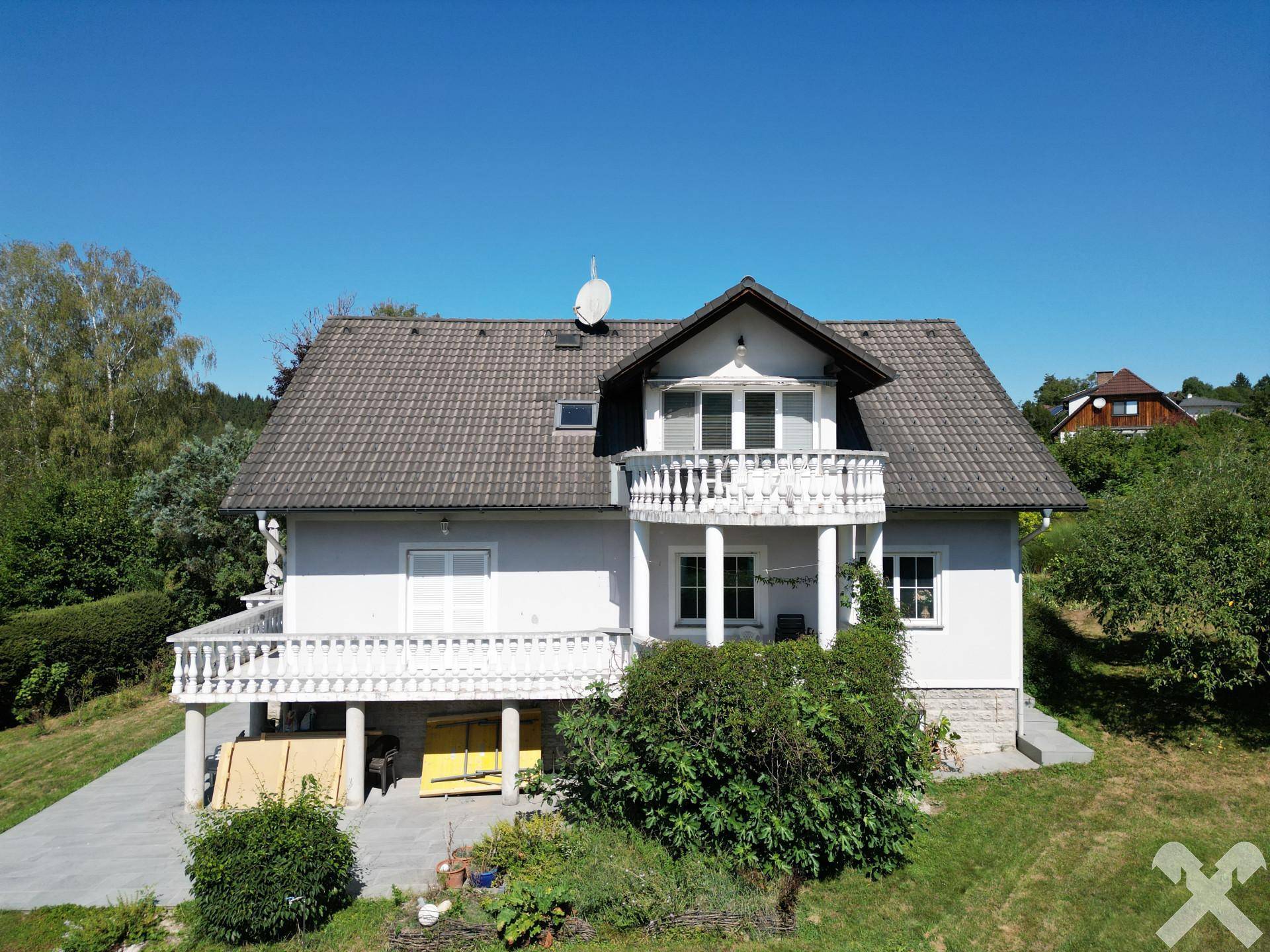 Ansicht des Einfamilienhauses von vorne mit Balkonen und gepflegtem Gartenbereich.