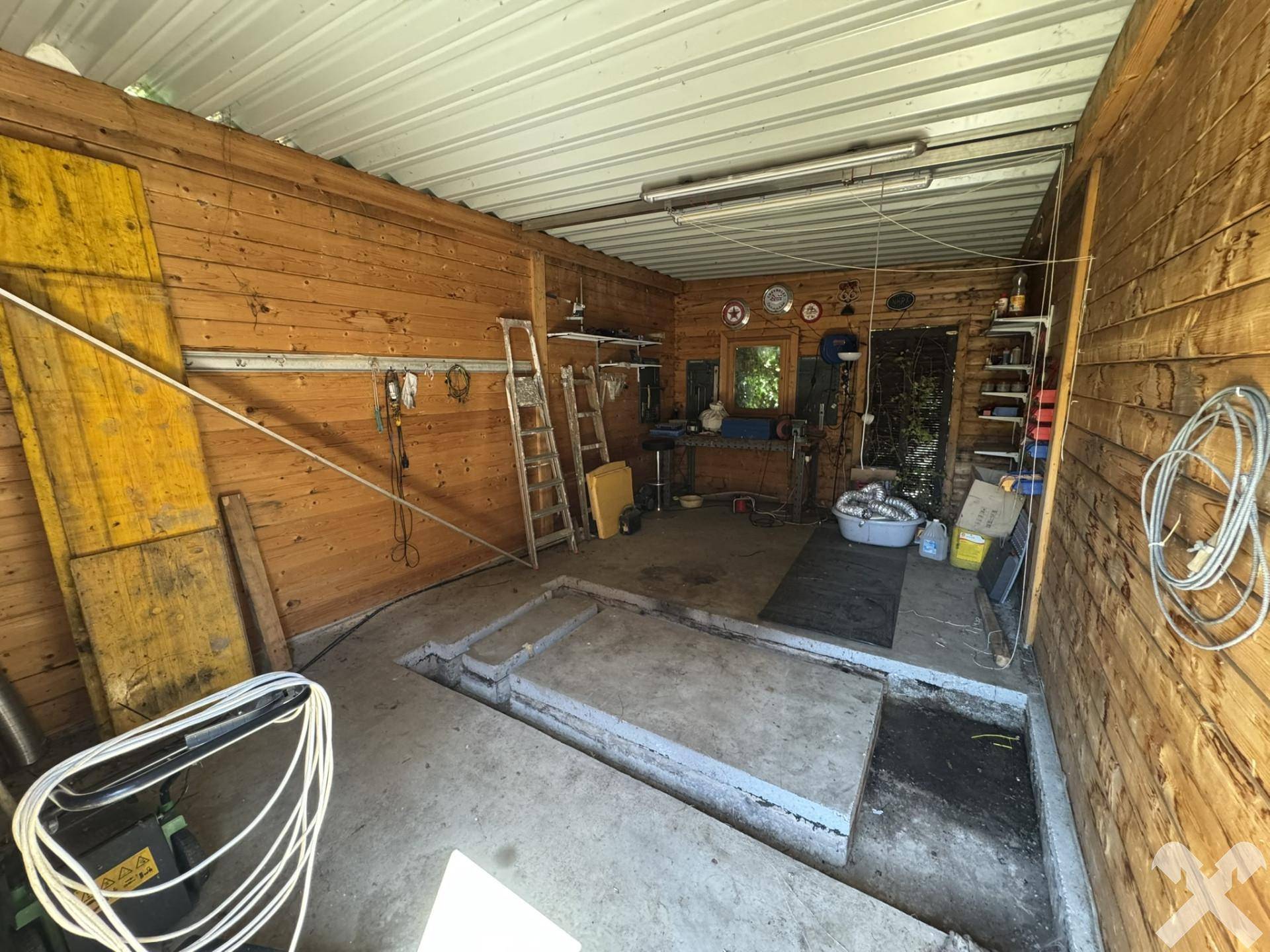 Geräumige Holzgarage mit Werkstattbereich und einer Grube für Fahrzeugwartung, funktional.