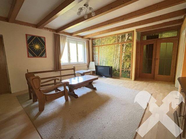 Gemütliches Wohnzimmer mit Holzbalkendecke, traditionellen Möbeln und einer Wanddekoration mit Birkenmotiv.