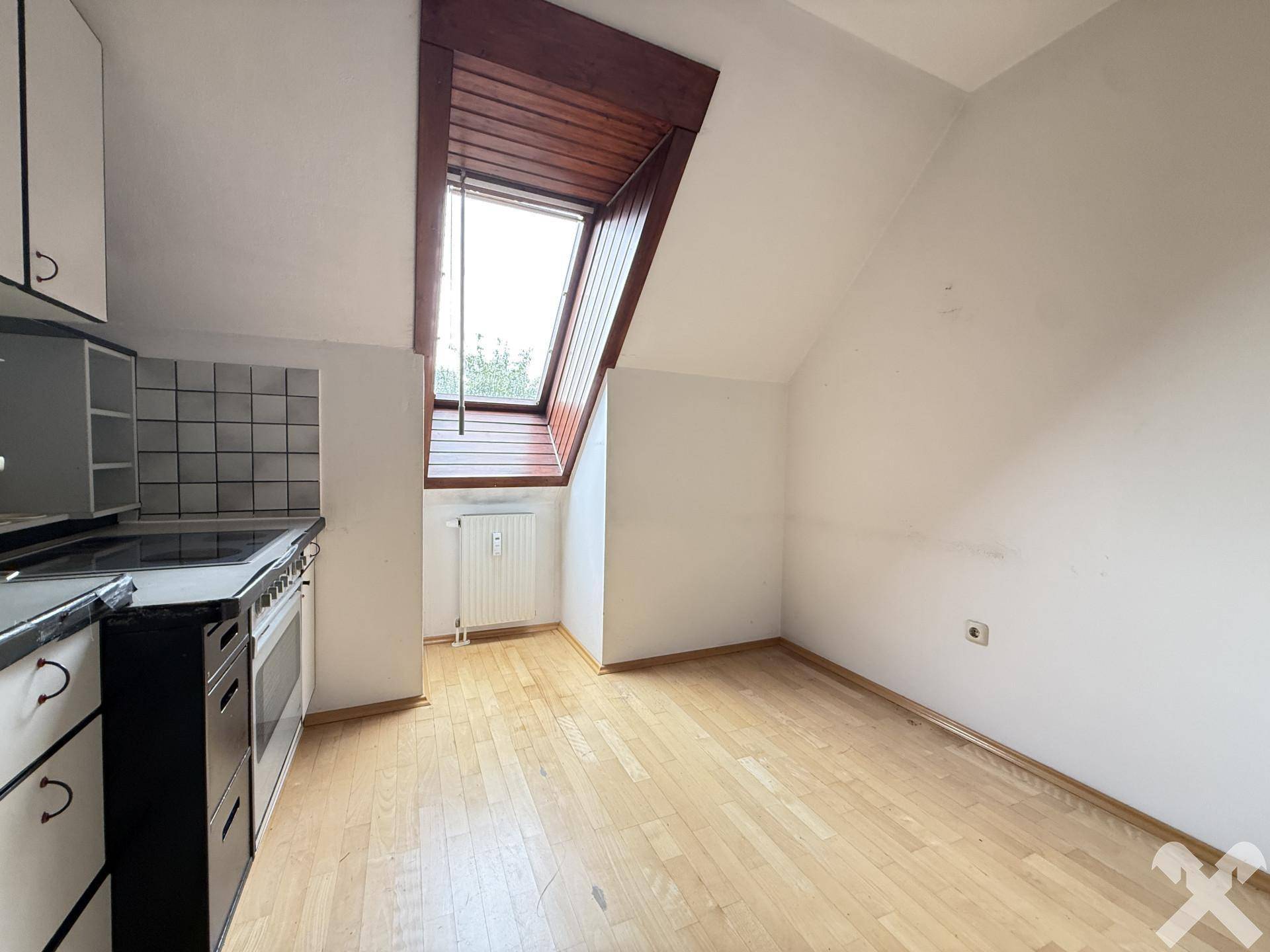 Kleine Küche im Dachgeschoss mit Herd, Schränken und einem Dachfenster für natürliches Licht.