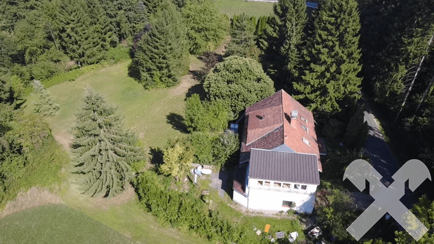Luftaufnahme des Anwesens mit Haus, Garten und angrenzenden Feldern, umgeben von Wald.