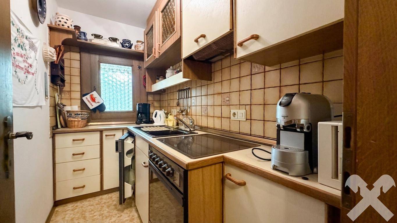 Kleine Küche im Landhausstil mit Holzschränken, Fliesenrückwand und Elektrogeräten.