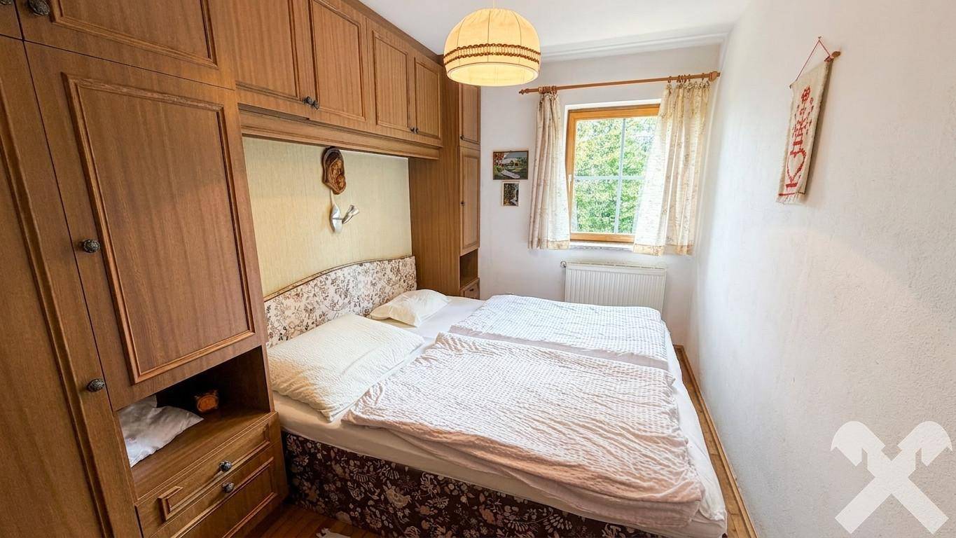 Schlafzimmer mit Einbauschränken aus Holz, Doppelbett und Fenster mit Blick ins Grüne.