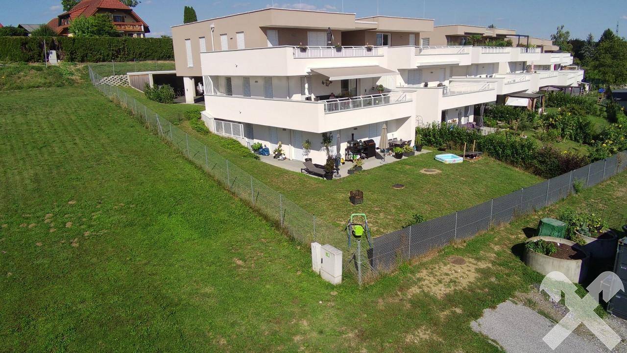 Moderne Wohnanlage mit mehreren Gebäuden, Balkonen, Terrassen und gepflegten Grünflächen.