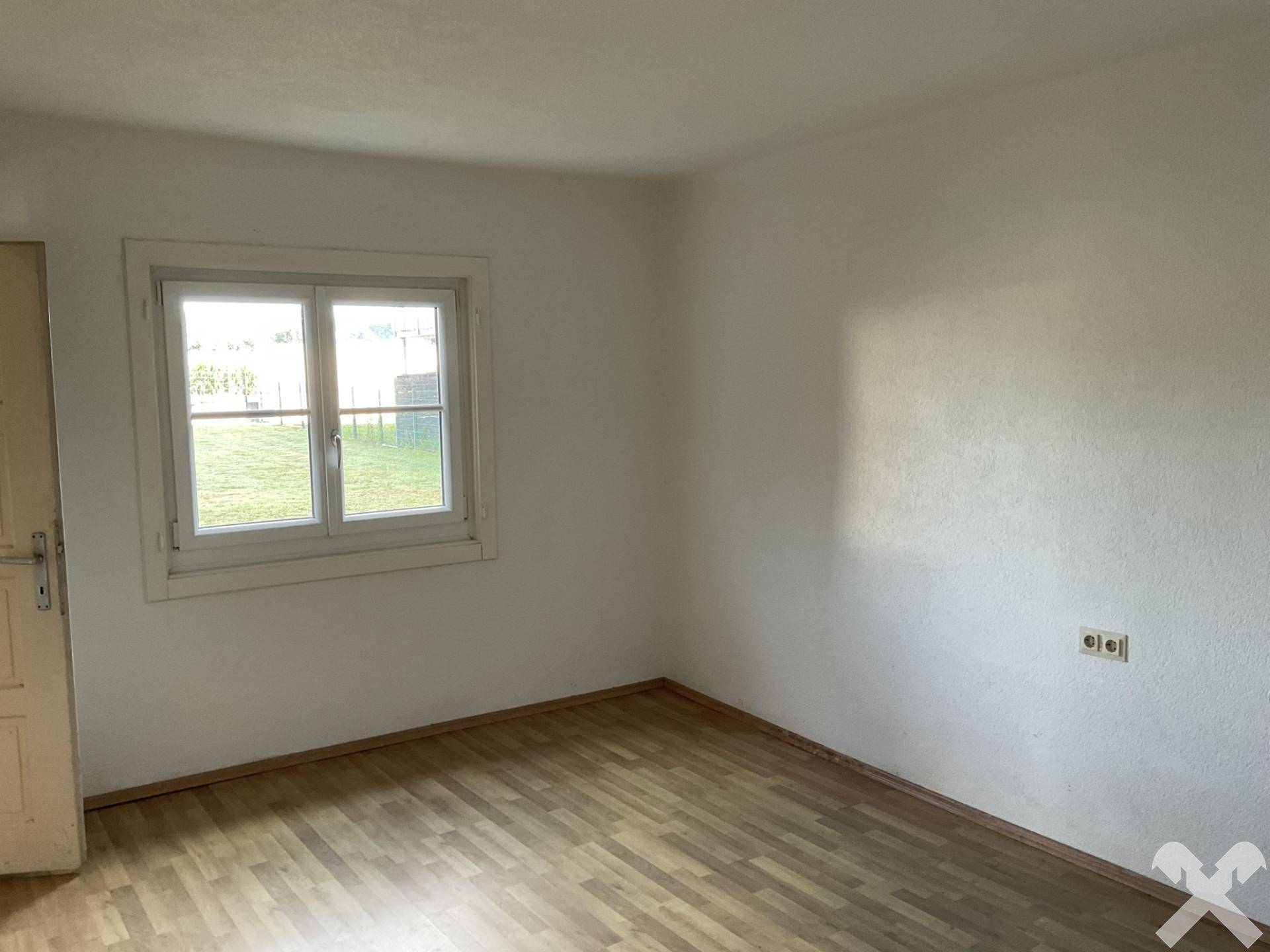 Lichtdurchfluteter Raum mit Fenster und Laminatboden, vielseitig nutzbar für Wohnzwecke.