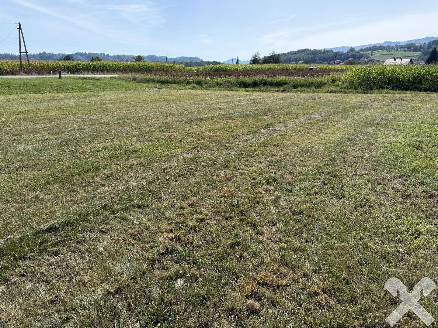 Offenes Feldgrundstück mit Wiese und Ackerland in der Ferne unter klarem Himmel.