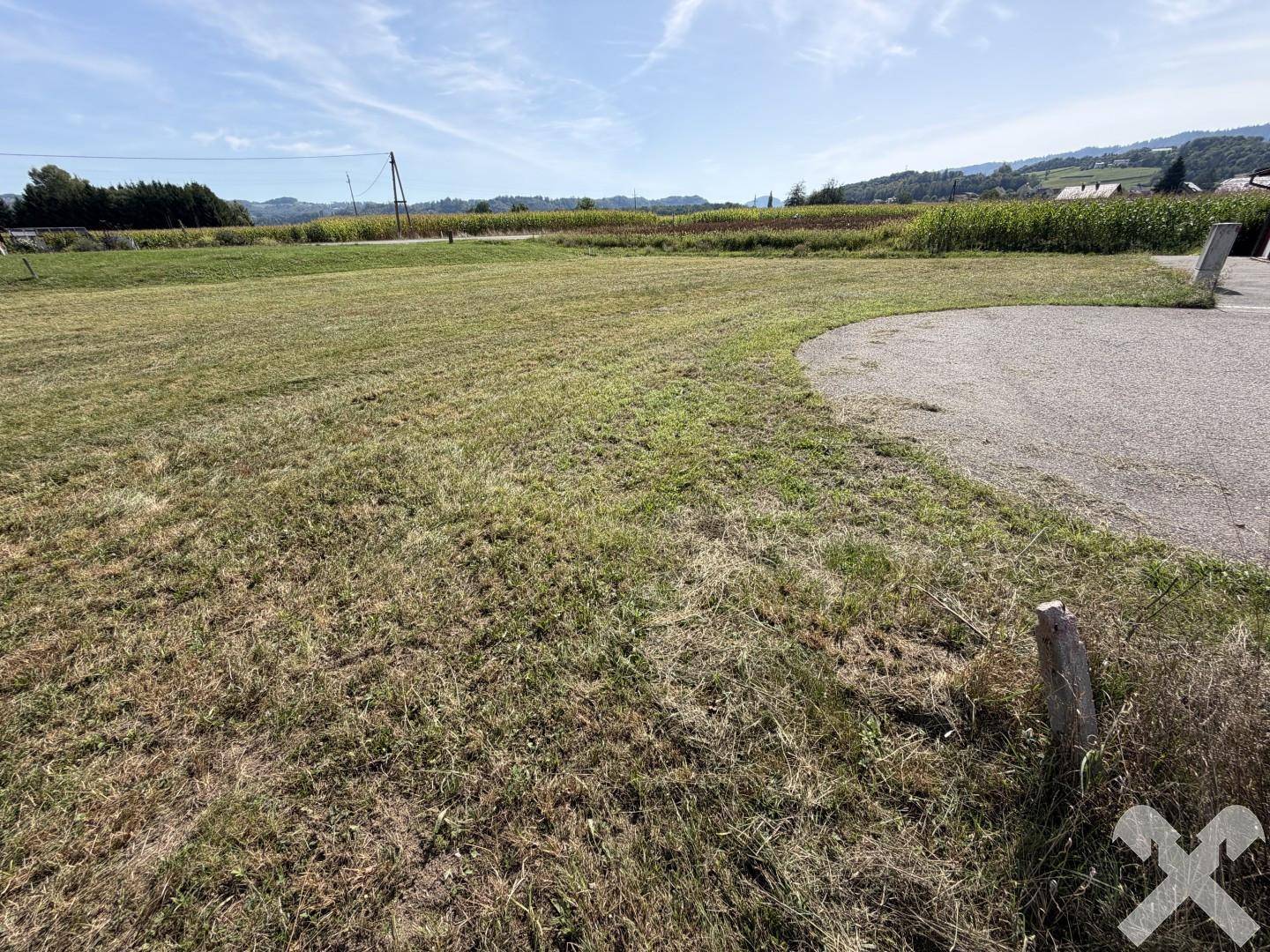 Grünes Grundstück mit angrenzender Zufahrt und weitem Blick über die ländliche Umgebung.