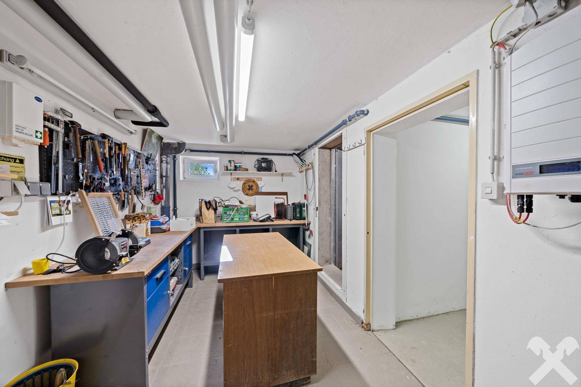 Geräumige Werkstatt im Untergeschoss mit umfangreicher Werkzeugwand und Arbeitsflächen.