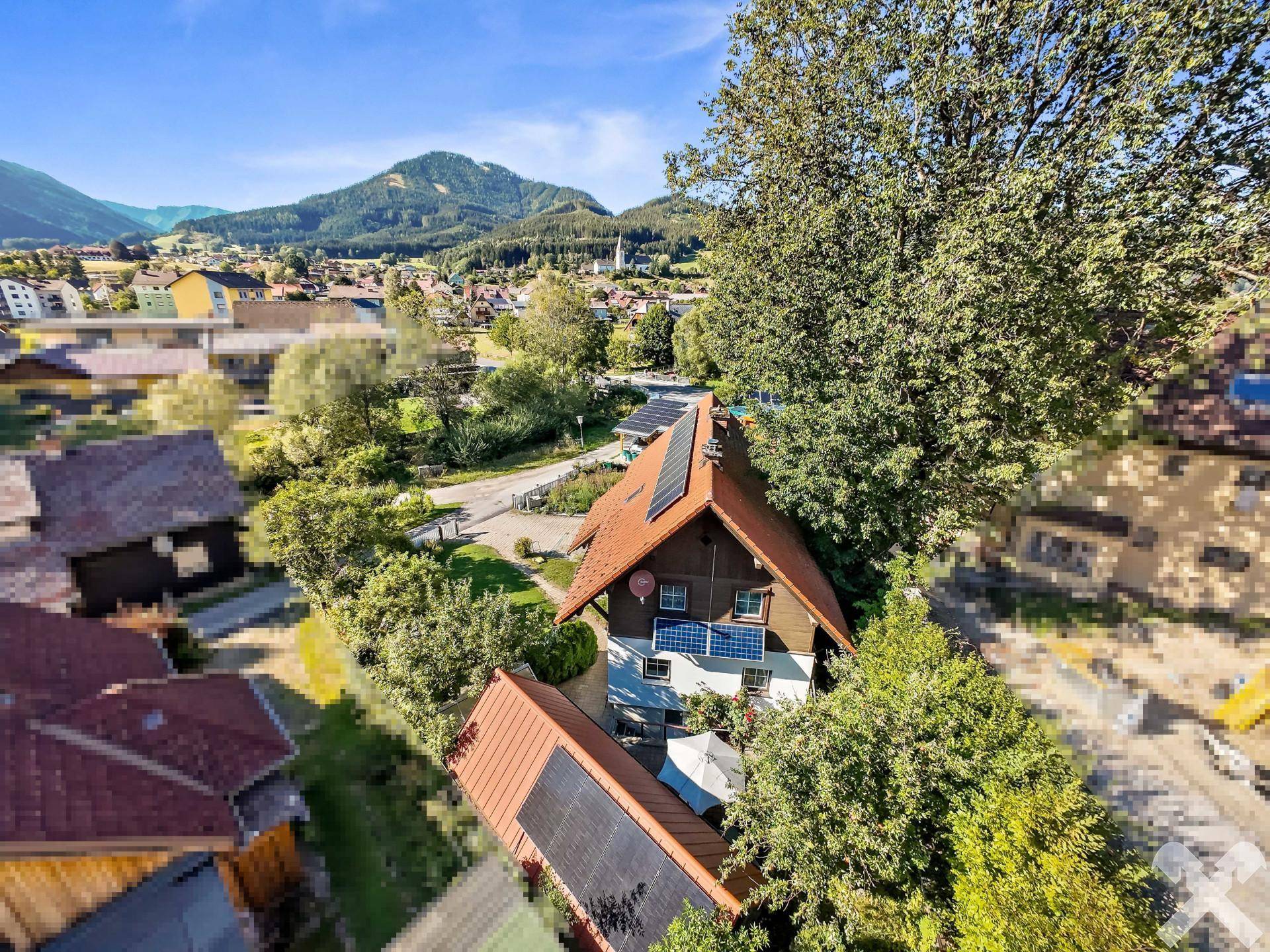 Panoramablick auf das Haus mit Solaranlage, umgeben von Natur und einem malerischen Dorf.