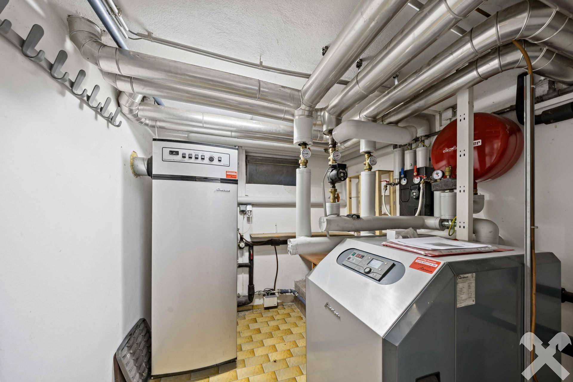 Heizungsraum im Keller mit modernen Heizungsanlagen und umfangreicher Rohrinstallation.