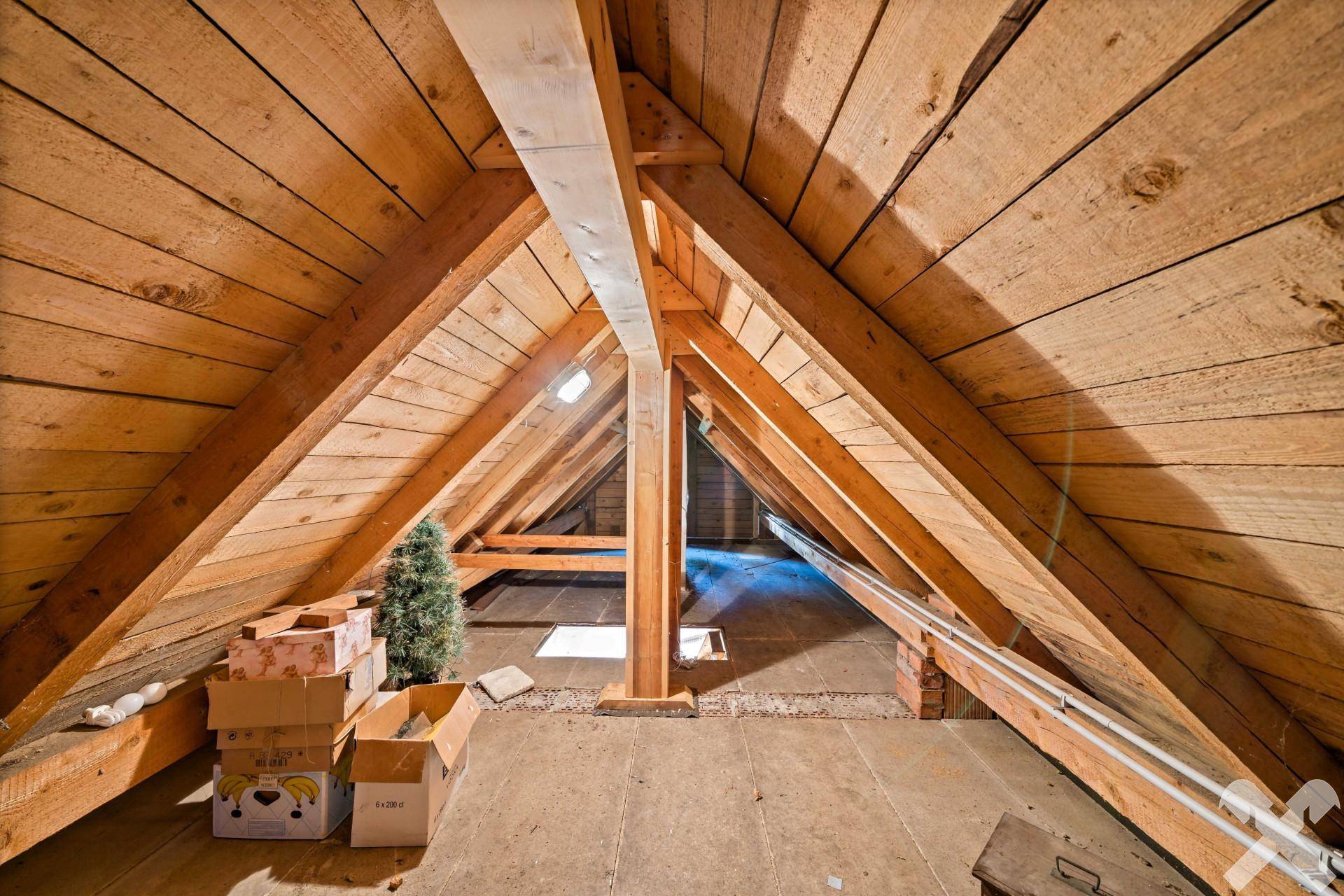 Dachboden mit sichtbaren Holzbalken und viel Stauraum unter dem Dach.