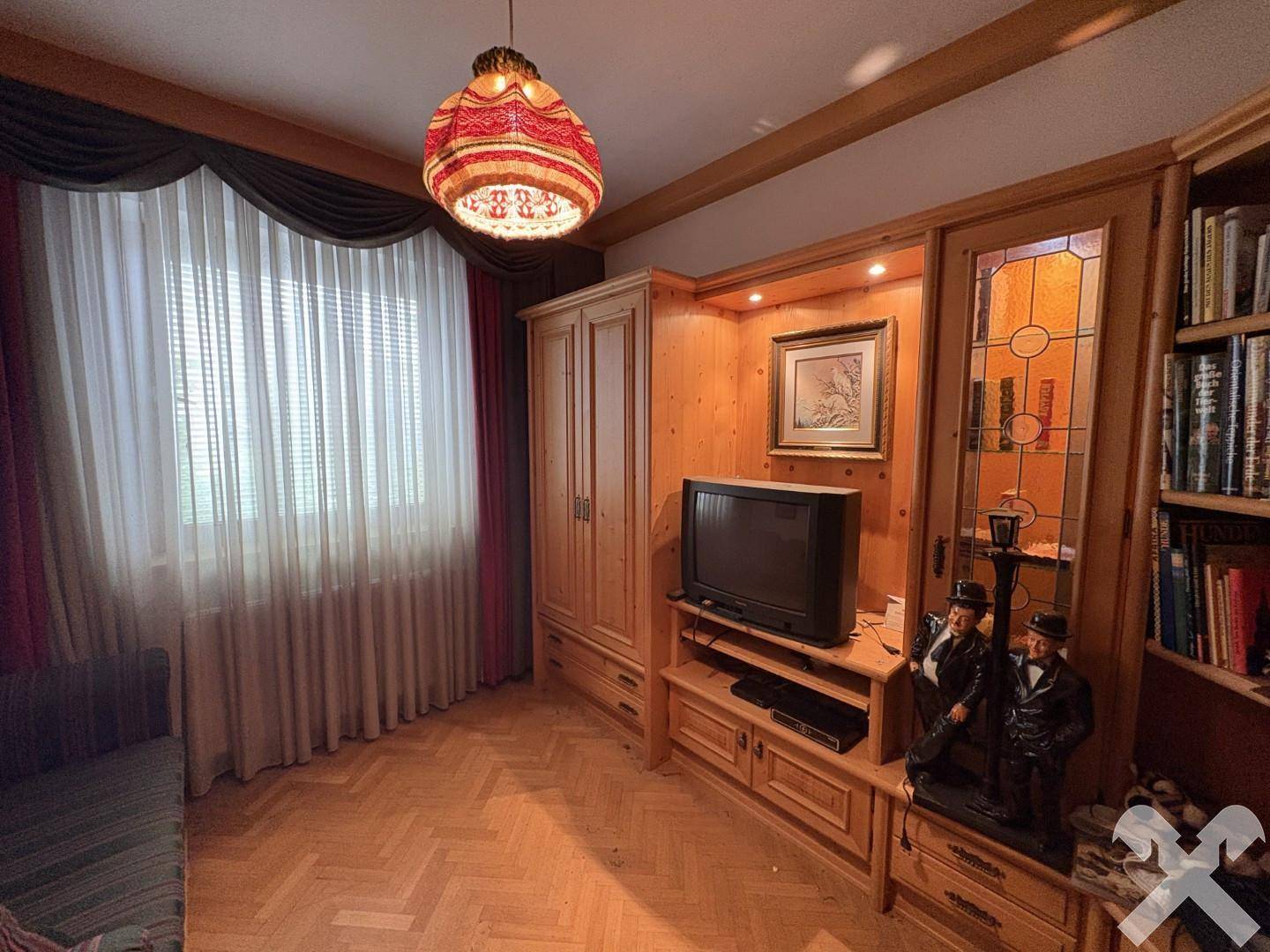 Helles Arbeitszimmer mit Holzvertäfelung, Bücherregal und Blick ins Grüne.
