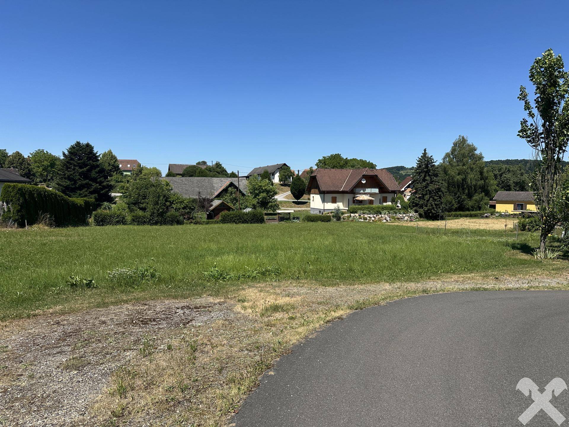 Weitläufige Grünfläche mit einer geschwungenen Straße im Vordergrund und Häusern am Horizont.