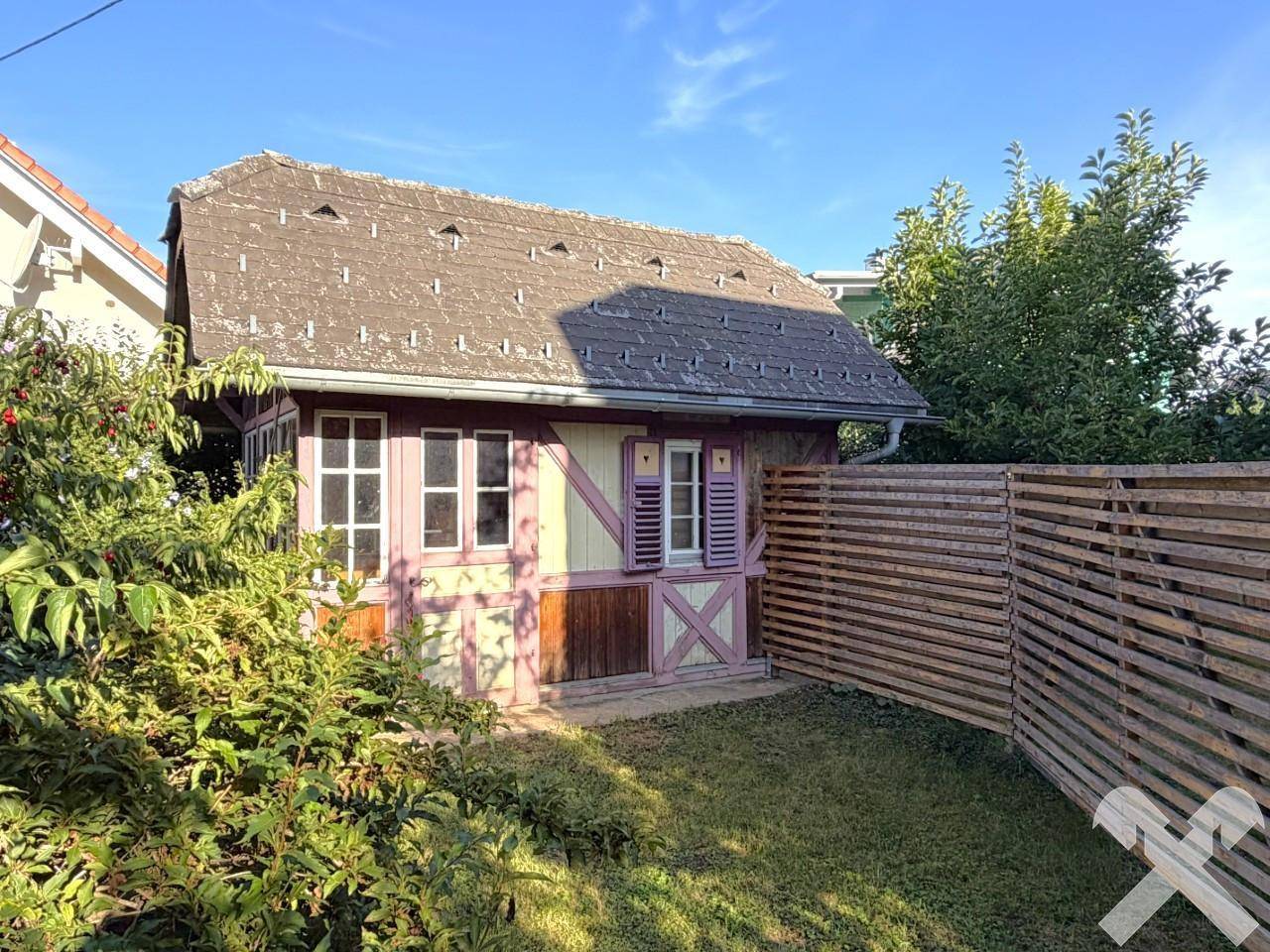 Kleines Gartenhaus im traditionellen Stil mit Holzelementen und einem gepflegten Rasenbereich.