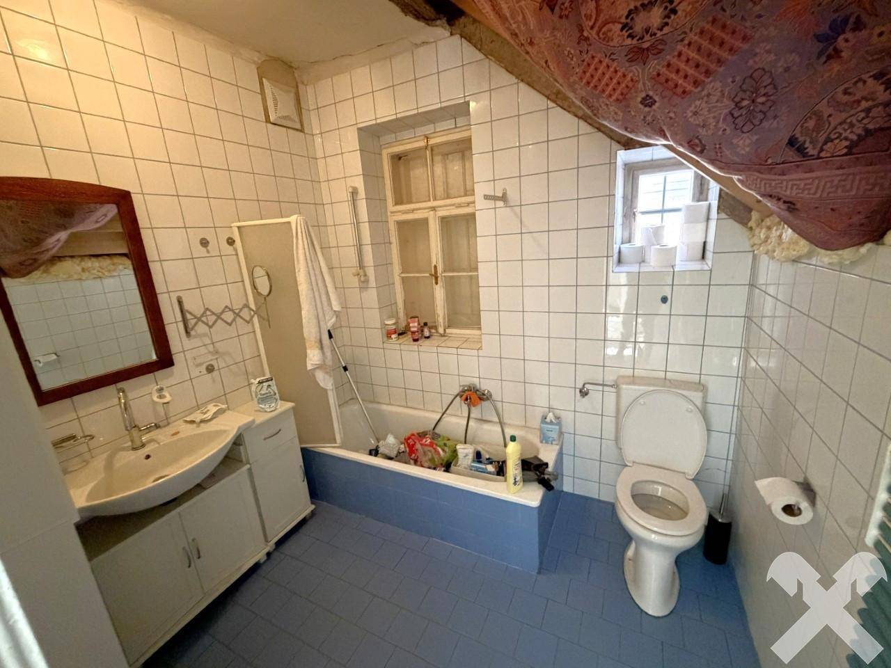 Badezimmer im älteren Stil mit blauen Fliesen, Badewanne und Fenster.