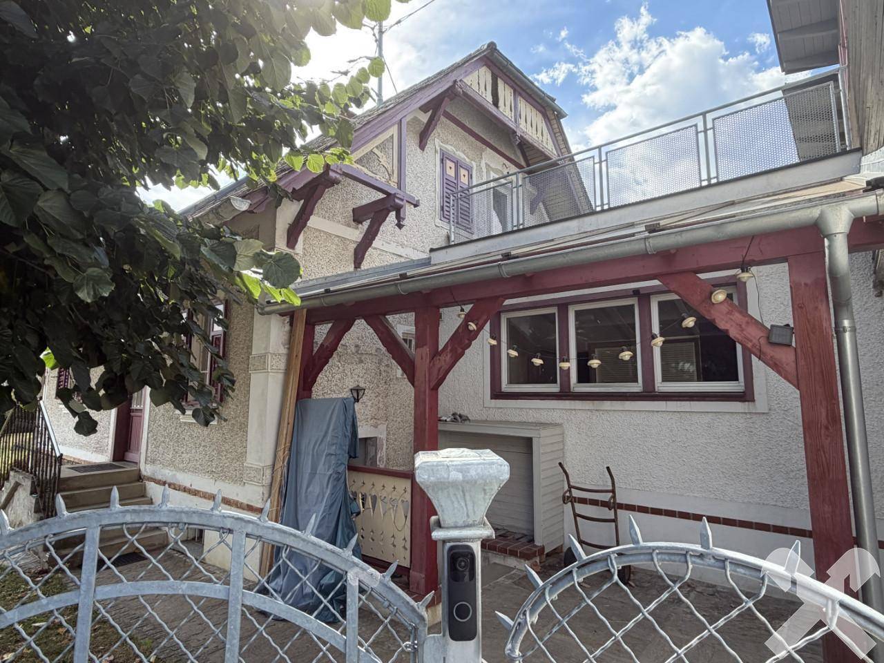 Detailansicht des Hauses mit überdachtem Eingangsbereich und einem Balkon mit Metallgeländer im Obergeschoss.