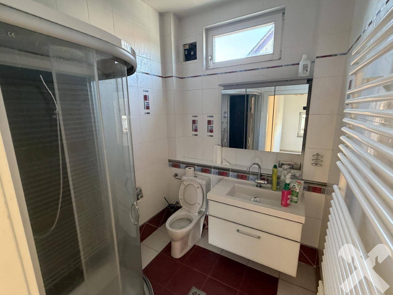 Modernisiertes Badezimmer mit Duschkabine, Waschtisch und beheiztem Handtuchhalter.