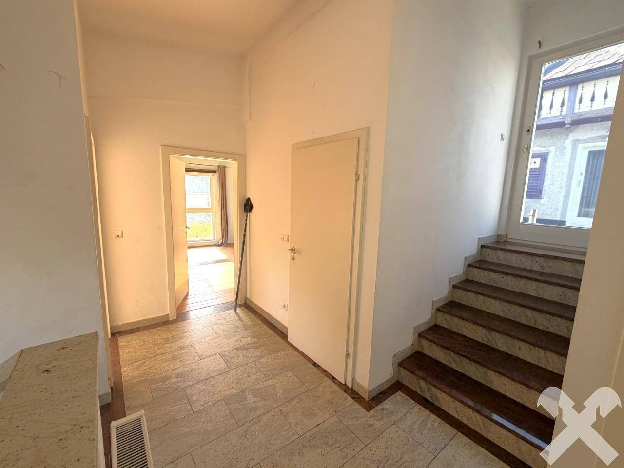 Eingangsbereich mit Steinfliesenboden, Treppe und Zugang zu weiteren Räumen.