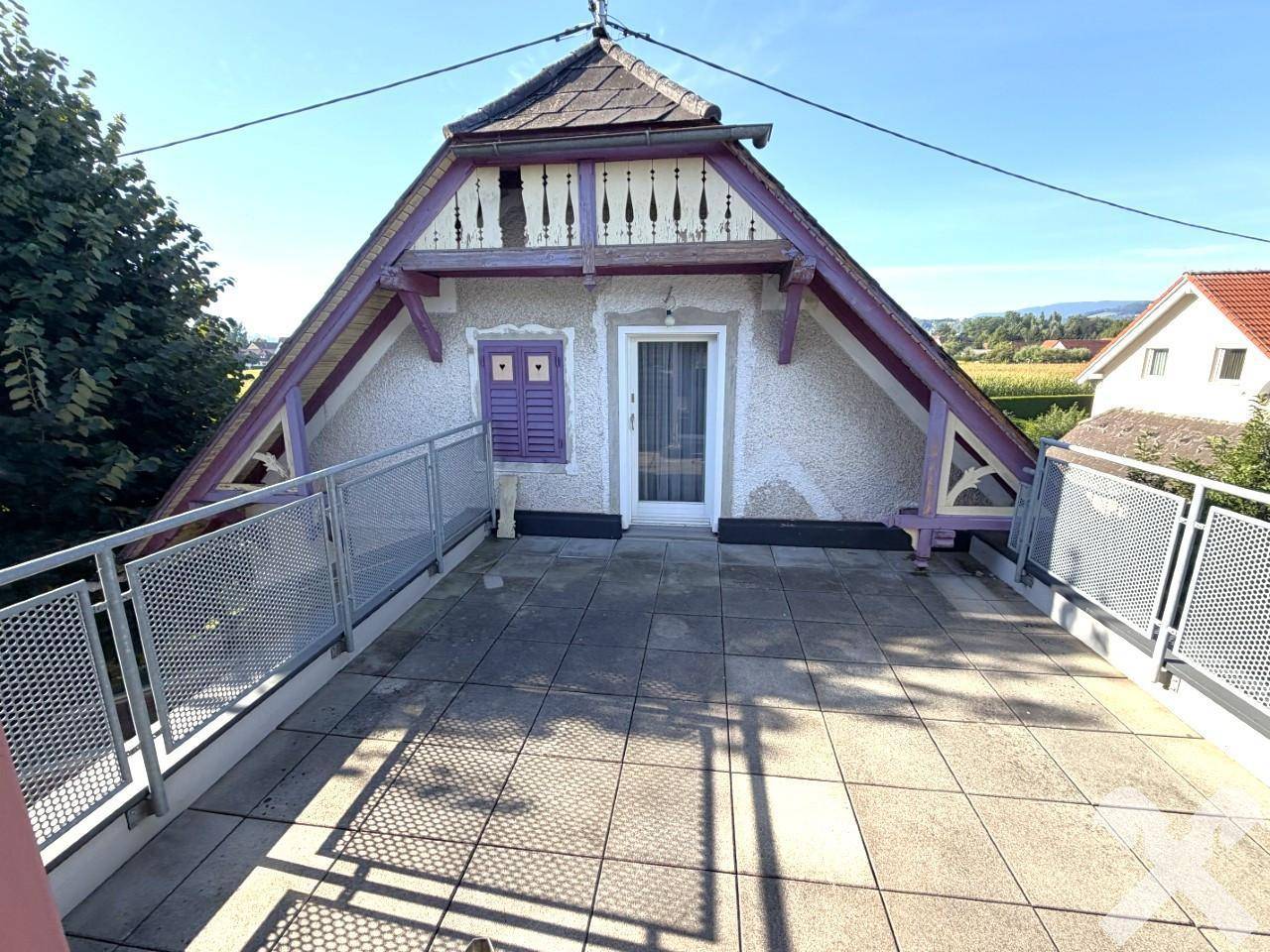 Dachterrasse des älteren Hausteils mit Fliesenboden und dekorativem Geländer.