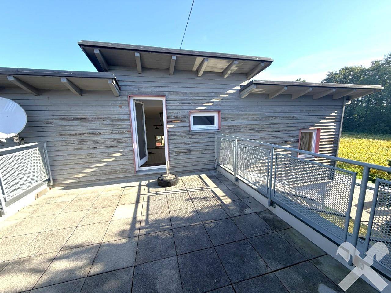 Große Dachterrasse mit Fliesenboden und Metallgeländer, zugänglich vom Obergeschoss.