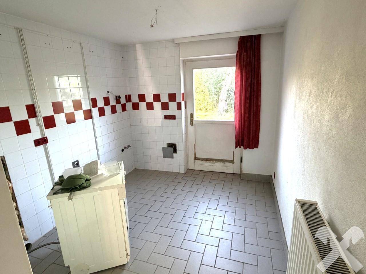 Hauswirtschaftsraum mit Fliesenboden, Waschmaschinenanschluss und Zugang zum Garten.