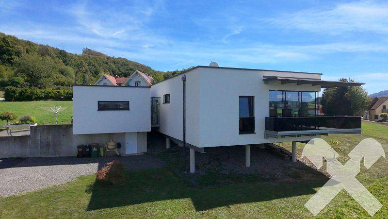 Ansicht des modernen Hauses von der Seite mit Zufahrt und Blick auf die umliegende Landschaft.