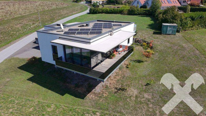 Modernes Haus mit Photovoltaikanlage auf dem Flachdach und großem Balkon mit Markise.
