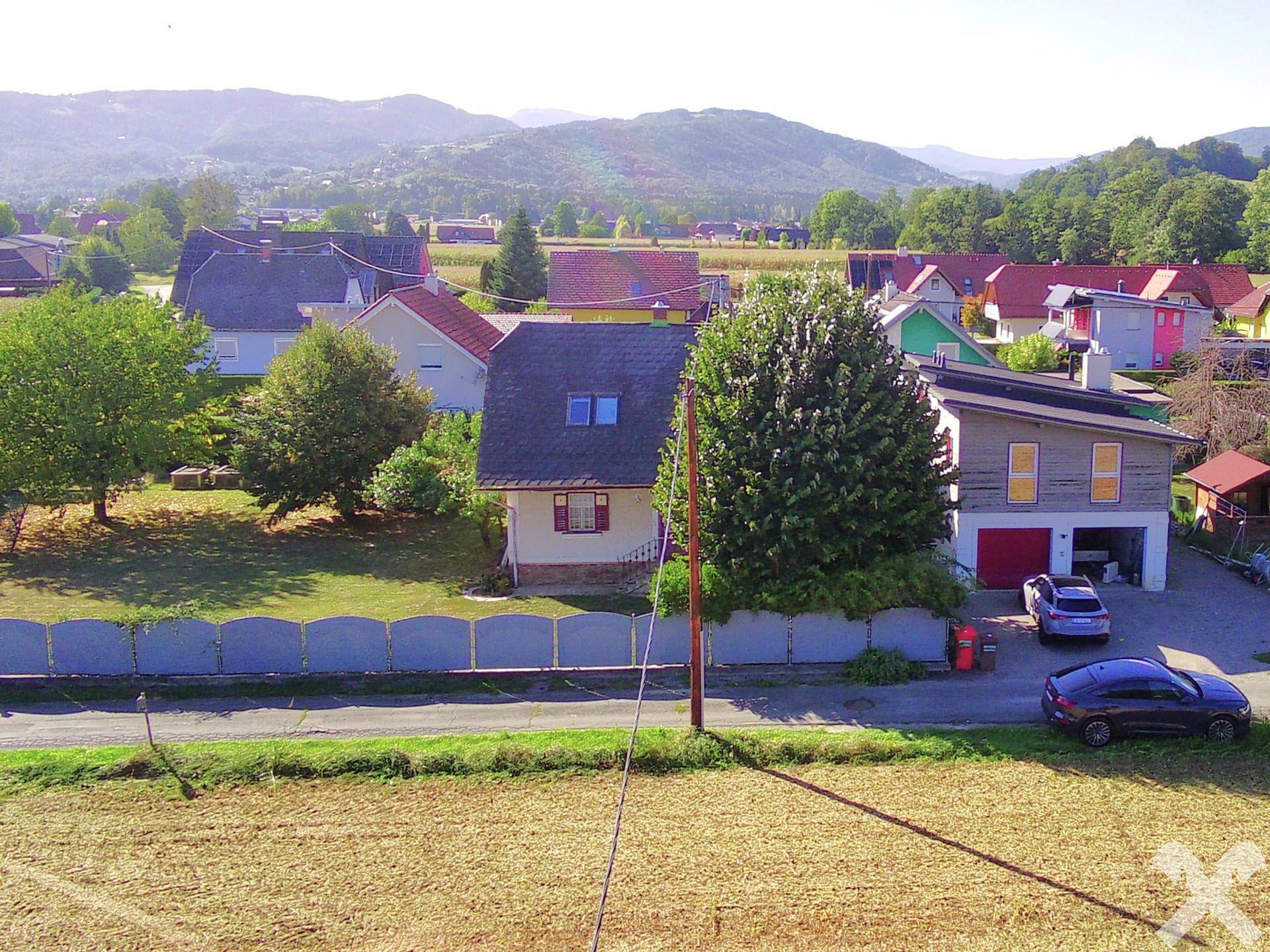 Weitläufige Luftaufnahme des Anwesens mit umliegender Wohnbebauung und grüner Hügellandschaft im Hintergrund.